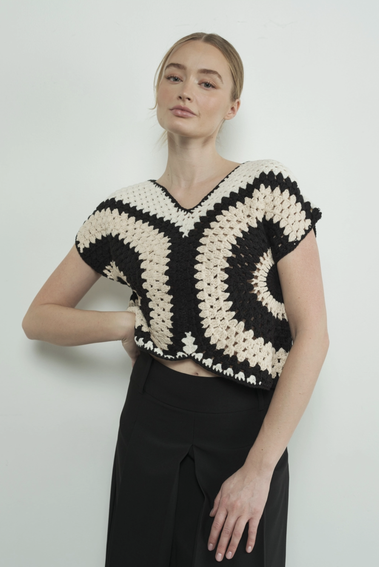 Model wearing the cream black and white crocheted sweater top
