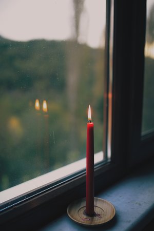 Holiday Red Candle in Window with Flame Reflecting in Glass