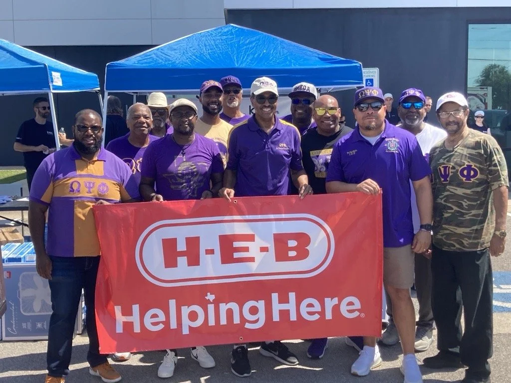 A group of people holding a H-E-B Helping here flag
