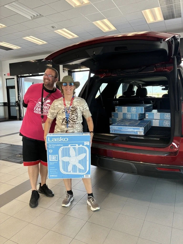 2 people standing in front of a trunk of fans