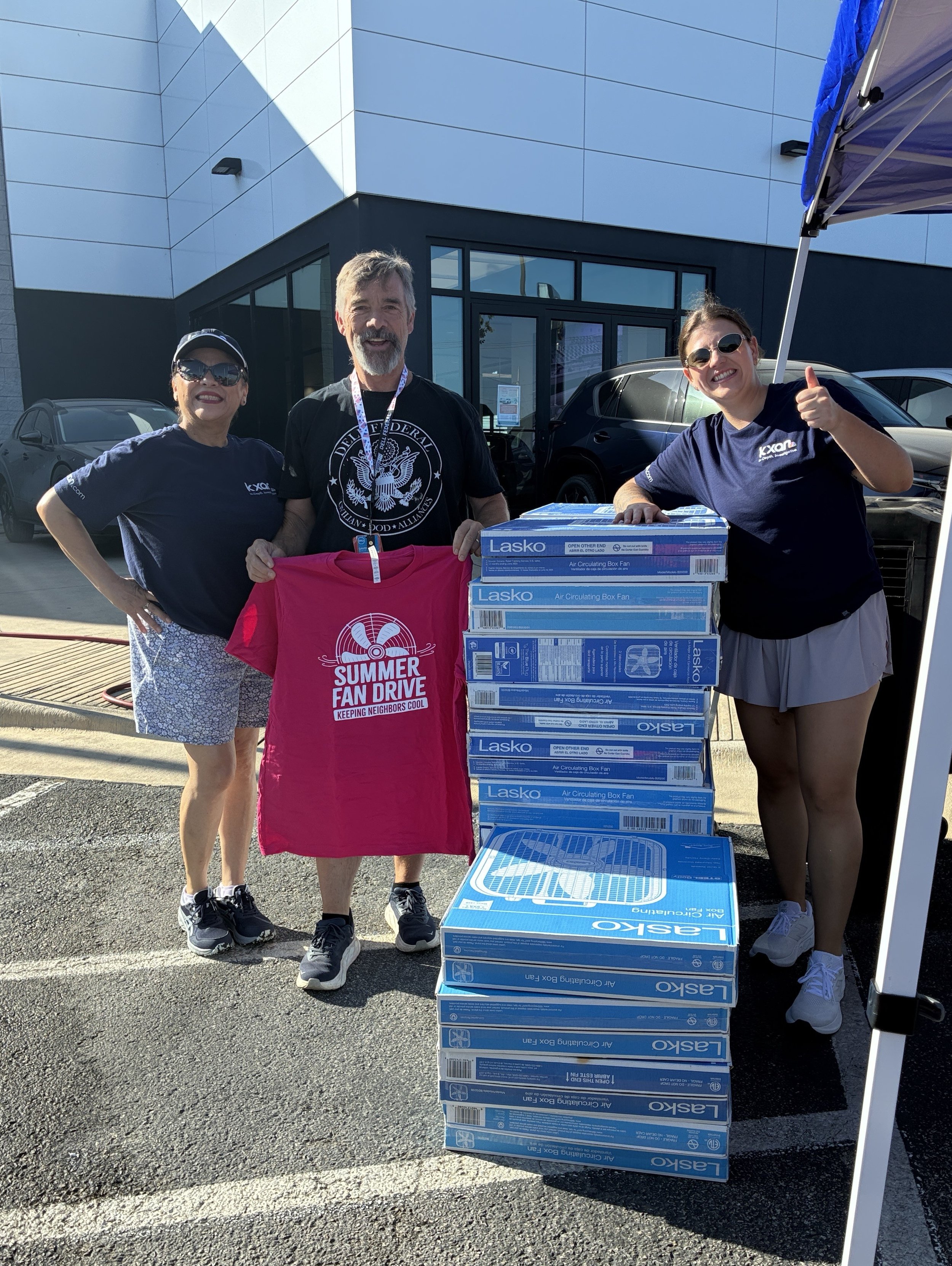 3 people standing by a stack of box fans