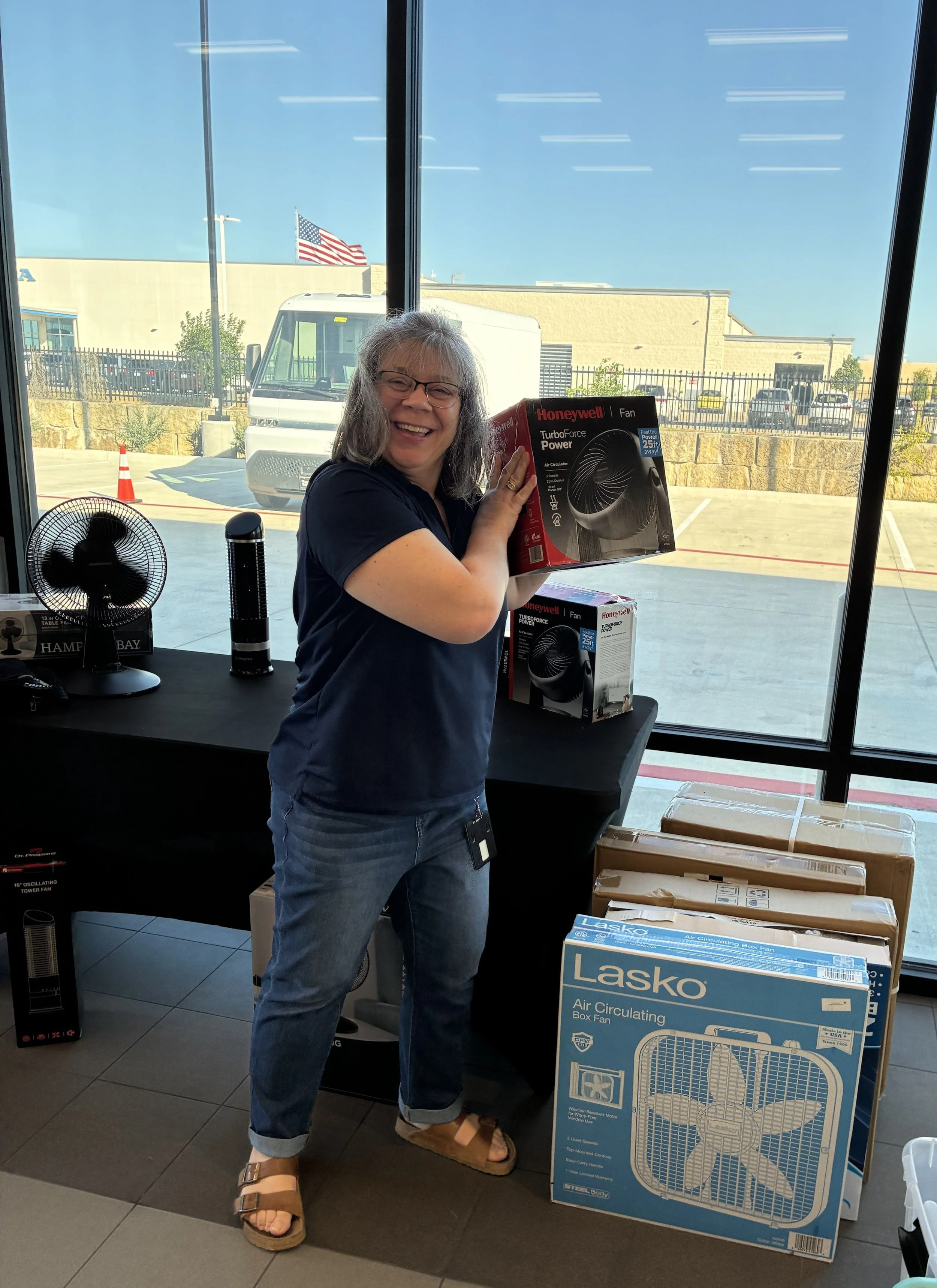 one person holding a desktop fan standing near boxes of fans