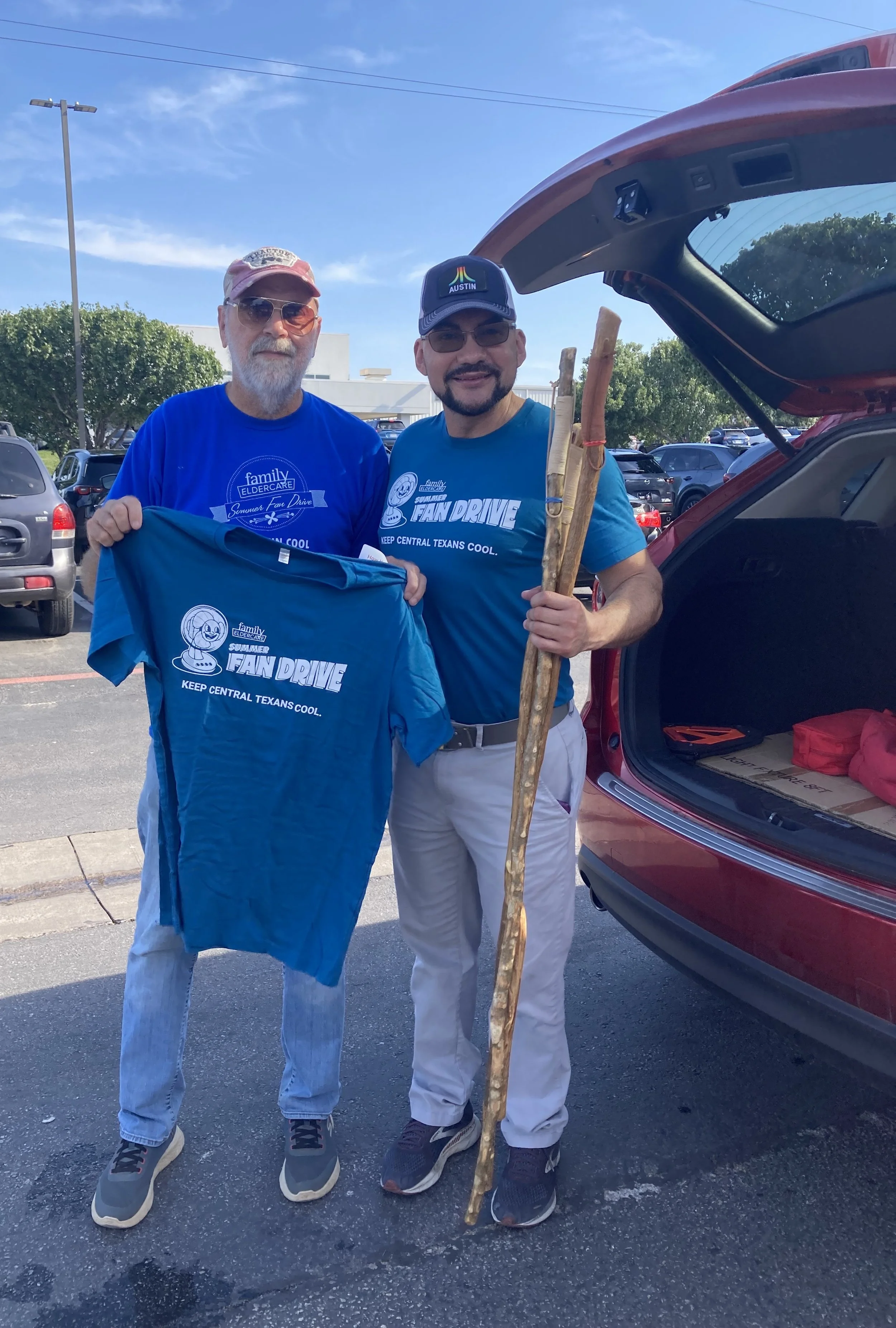 A guy holding a t-shirt and another guy holding walking sticks