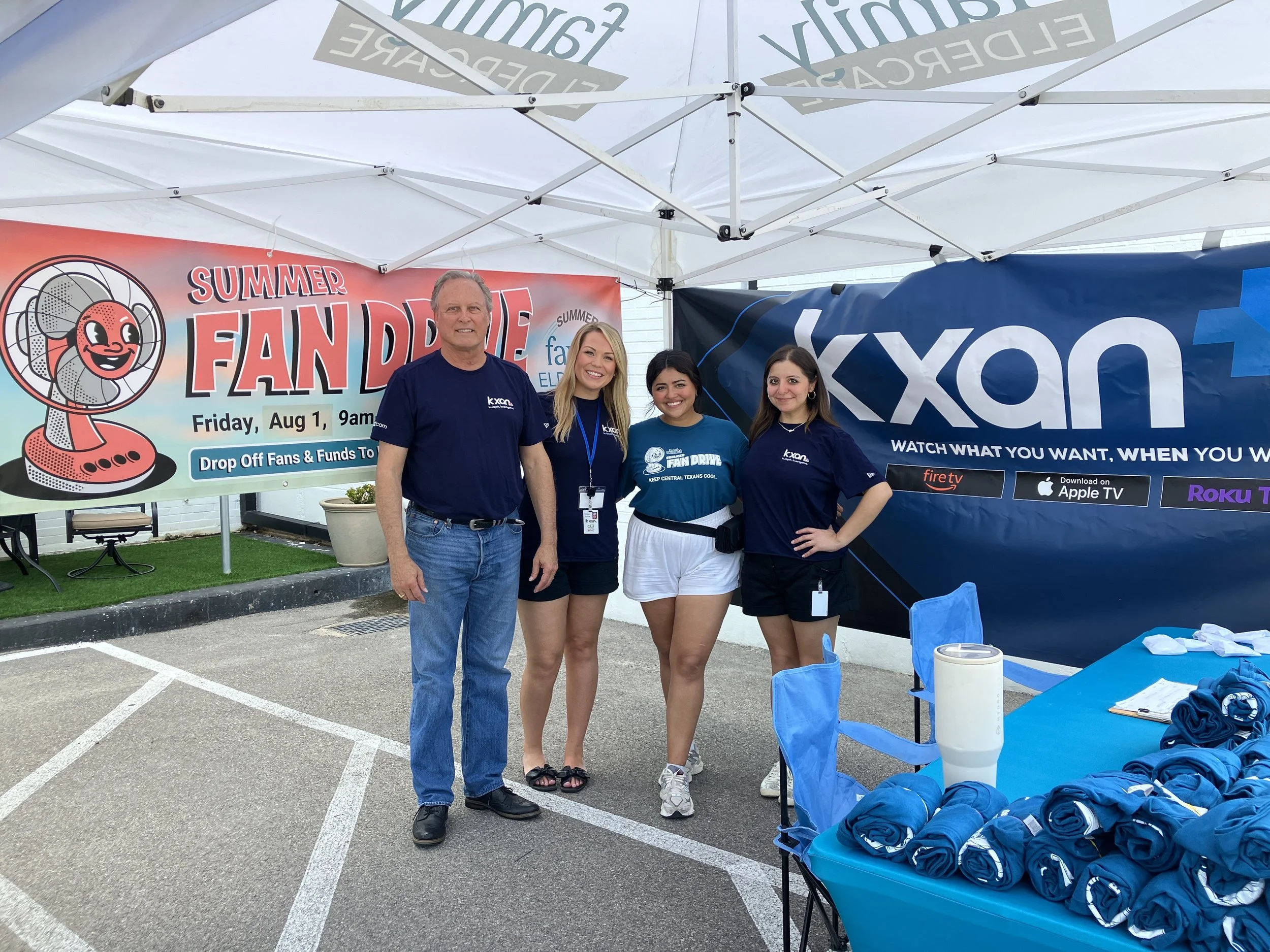 4 people standing under tent at fan drop off event