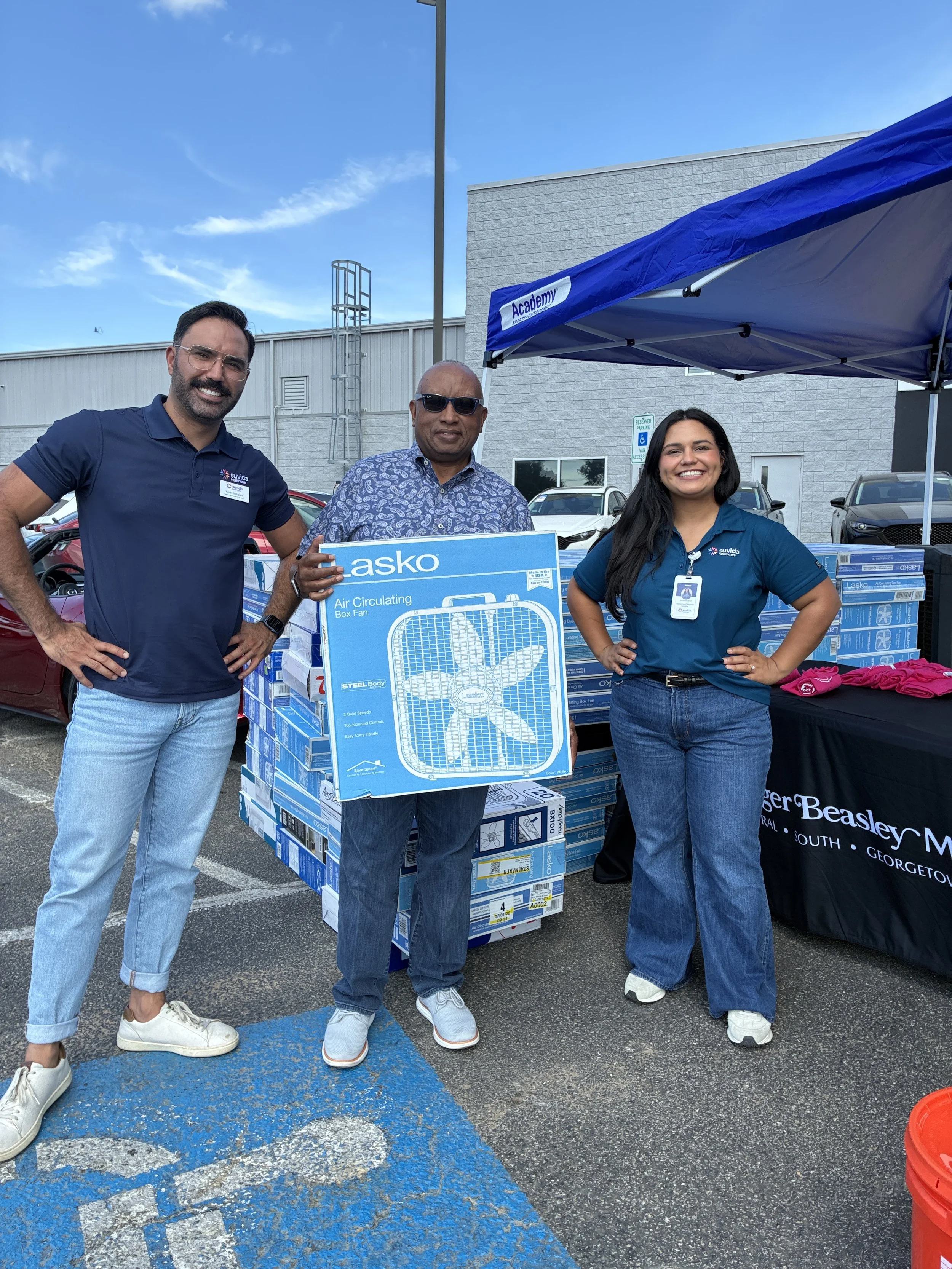 3 people with one holding a box fan