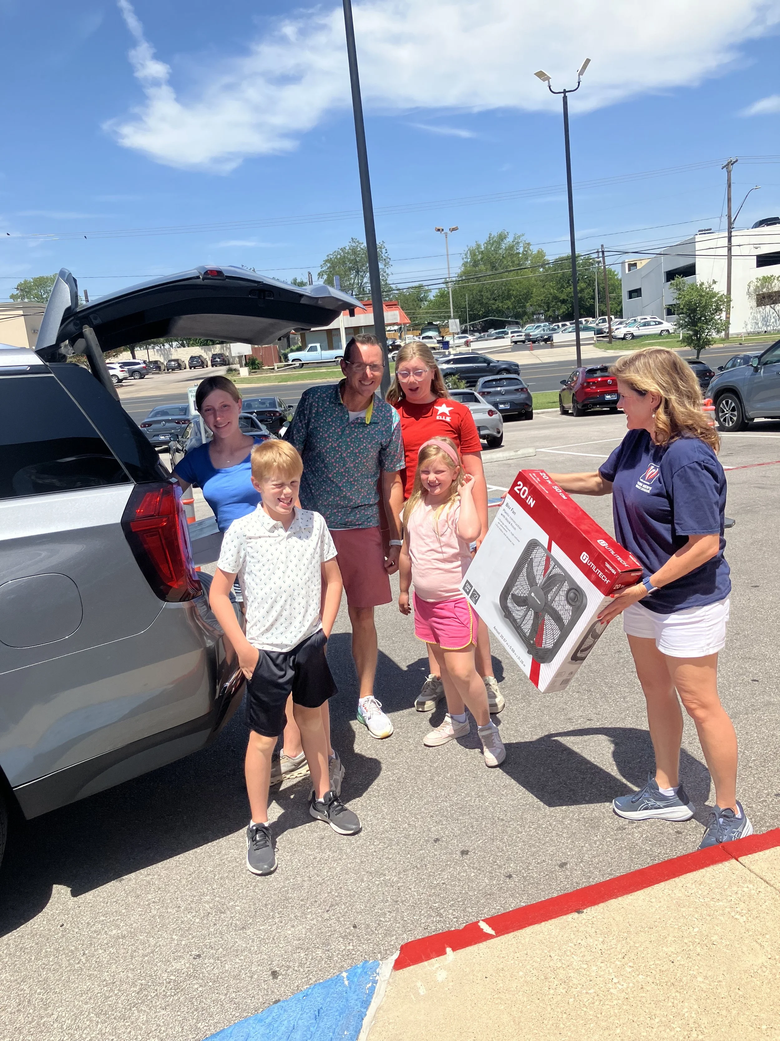A family unloading a fan from their car