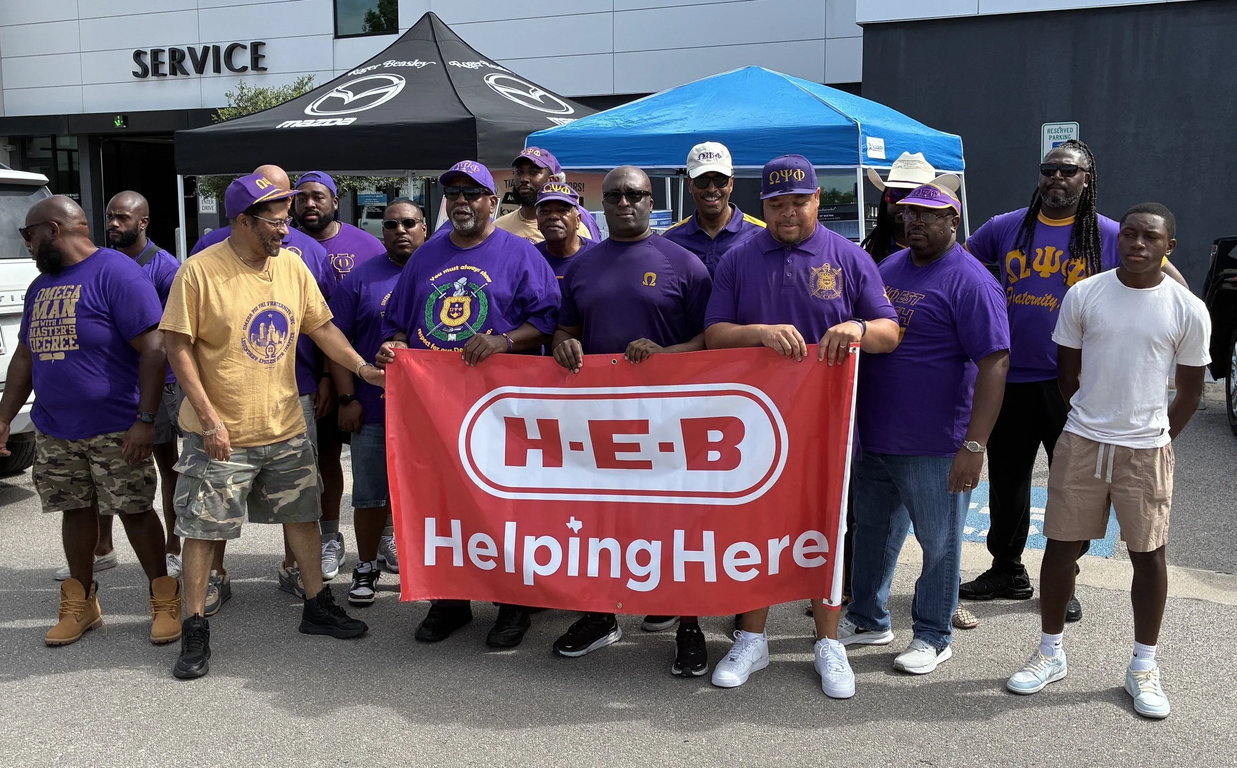 a group of people holding up a H-E-B Helping Here sign