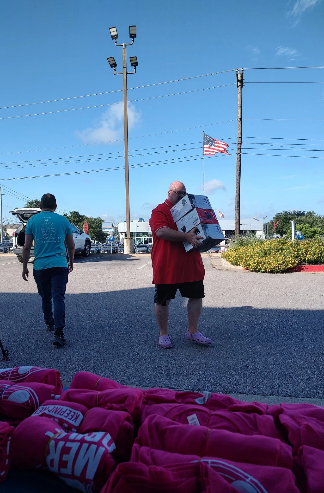 1 person walking away and one person carrying boxes of fans