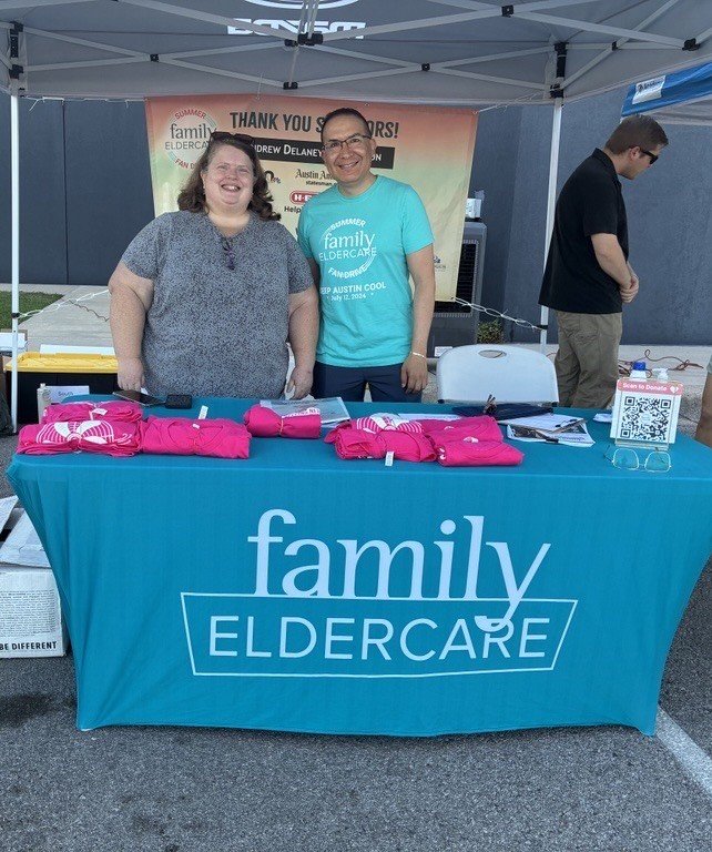 2 people standing behind a table that says "Family Eldercare"