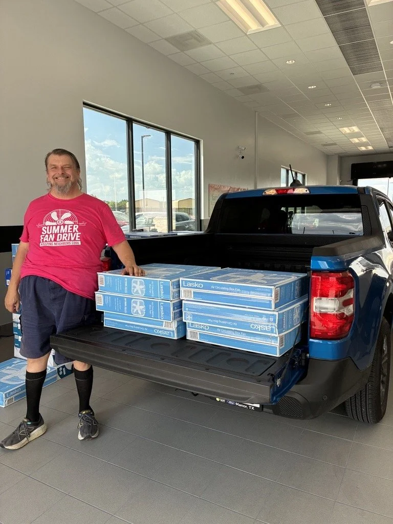 1 person standing in front of a truck bed filled with box fans