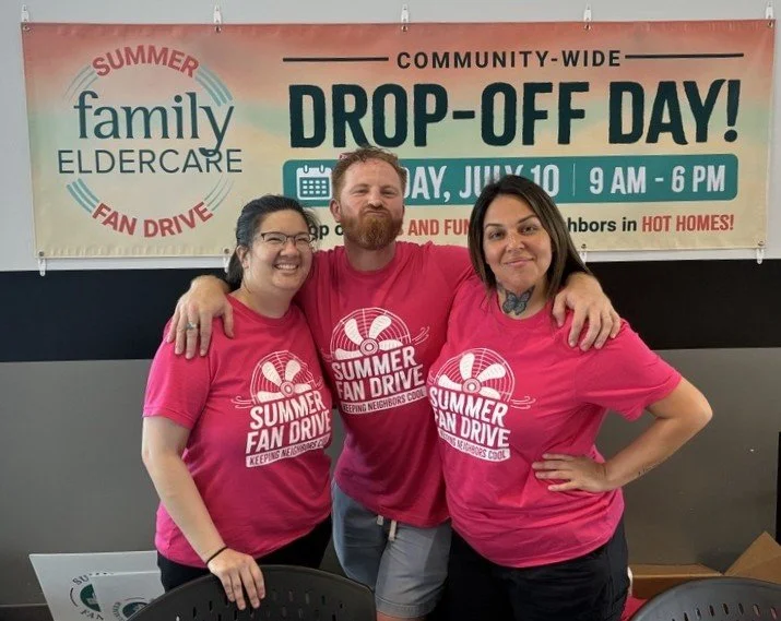 3 people standing in front of sign that says Drop Off Day Family Eldercare Summer Fan Drive