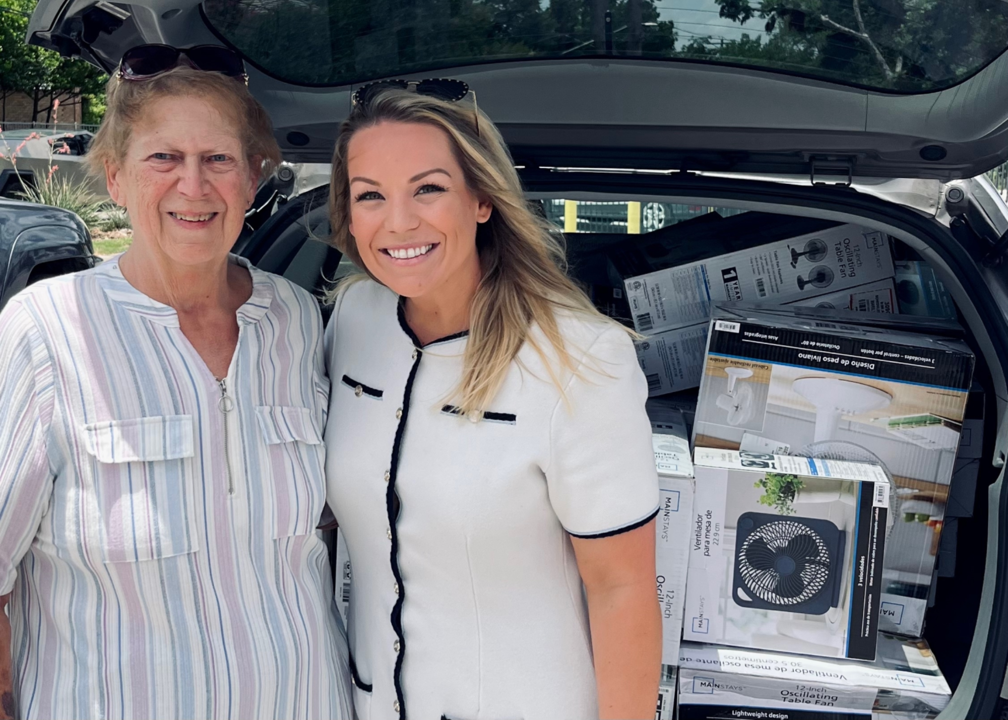 2 people in front of a trunk filled with box fans