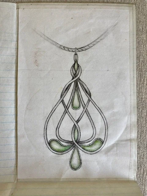 A sketch of an intricate silver necklace with green emeralds
