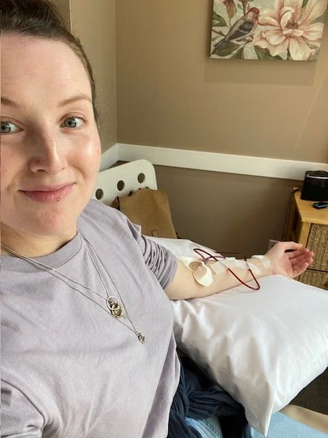 Sarah taking a selfie in a doctor's office with an IV in her arm