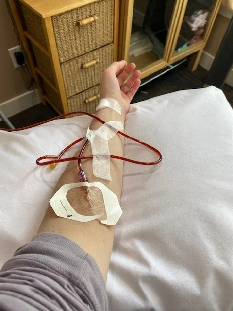 Sarah's left arm resting on a pillow with an IV line hooked up to it
