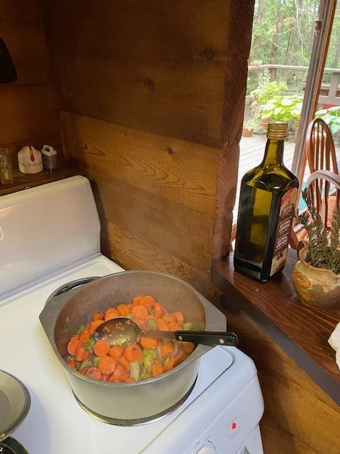A pot of vegetables cooking on a stove in a wood paneled kitchen