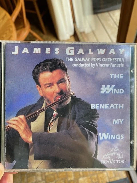 A cd case with a man from the 1980s playing a flute on the cover titled "James Galway: The Wind Beneath my Wings"