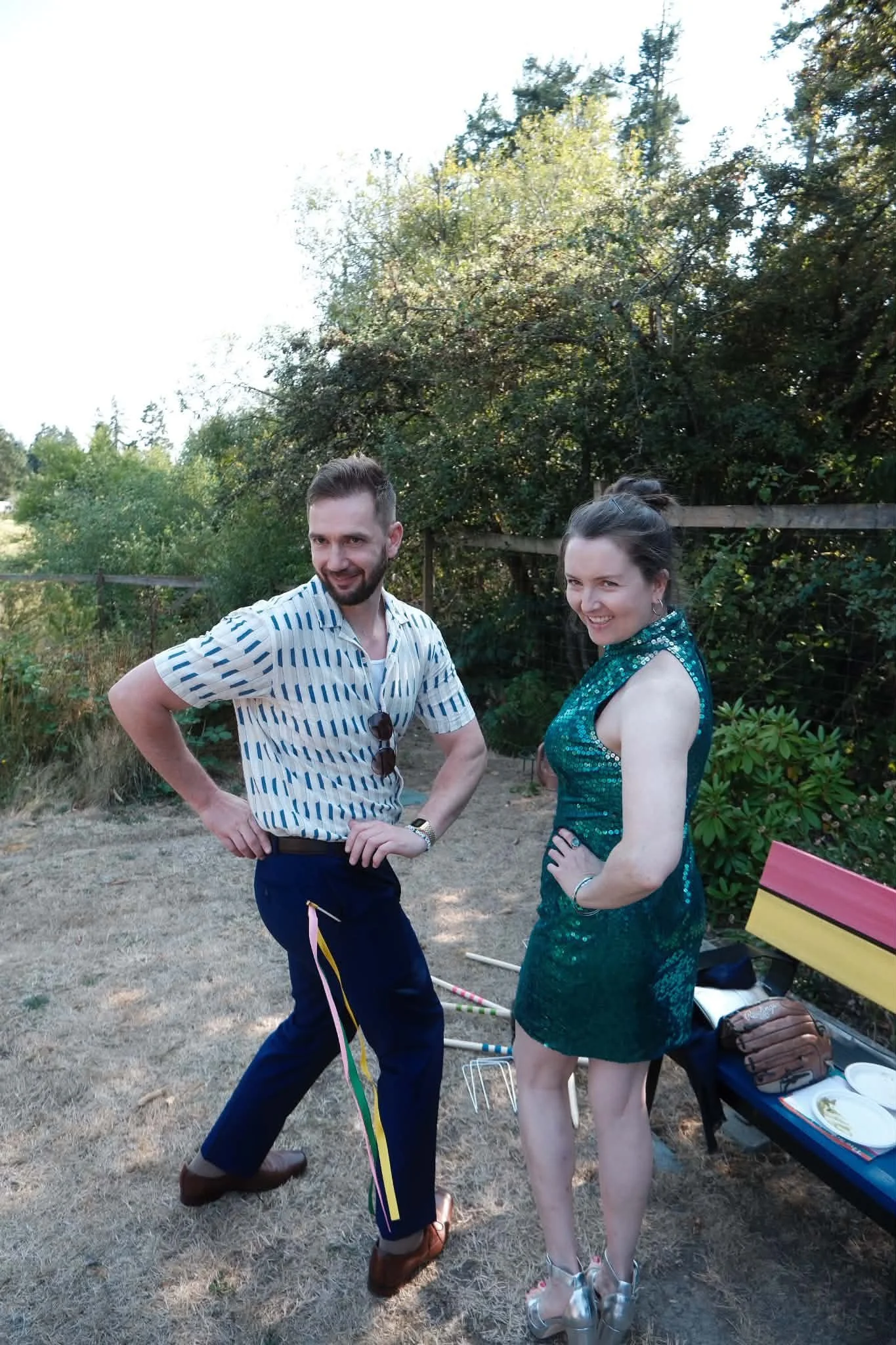 Sarah and her partner Nick in wedding guest attire turning around in an awkward pose with crossed eyes