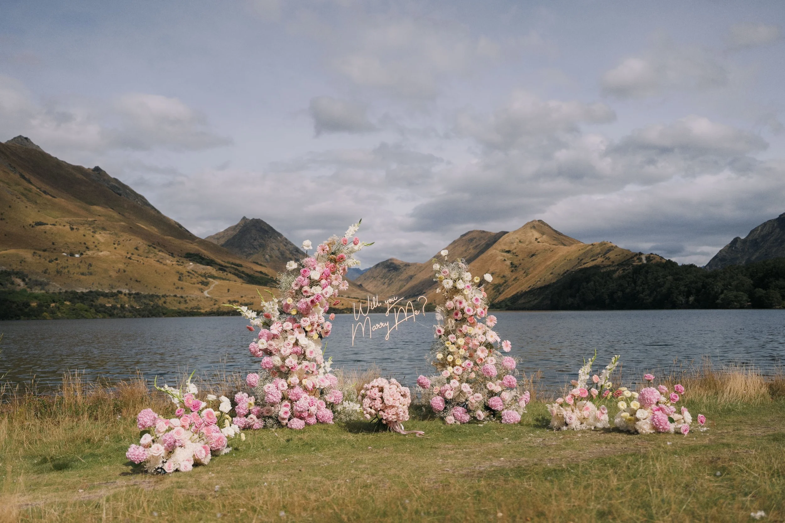 A lush pink roses wedding arch set up at Moke Lake for a marriage proposal. 
