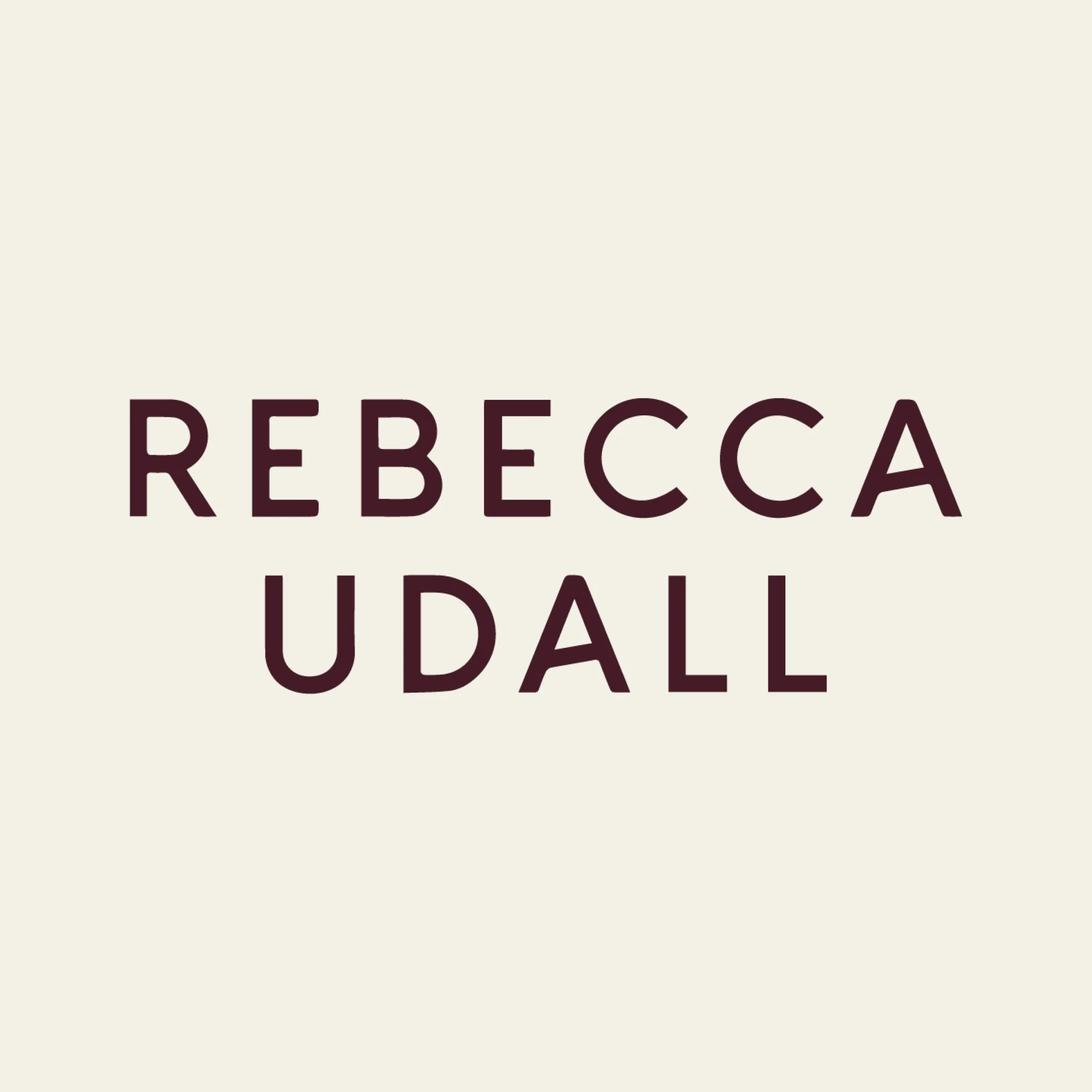 Part of a sign with the word "REBECCA" visible in dark capital letters on a light background.