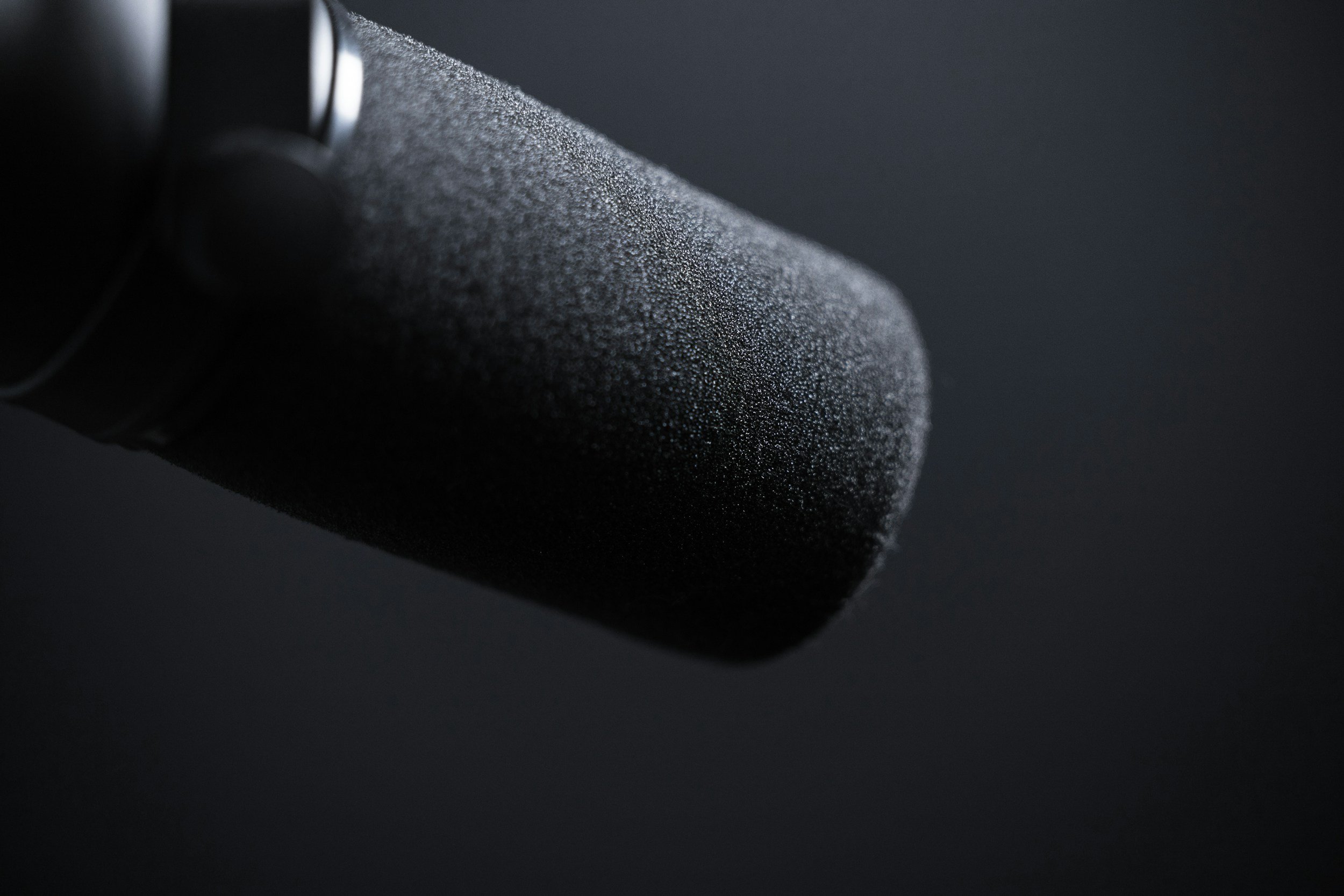 Close-up of a black object with a textured surface, partially obscured, against a dark background.