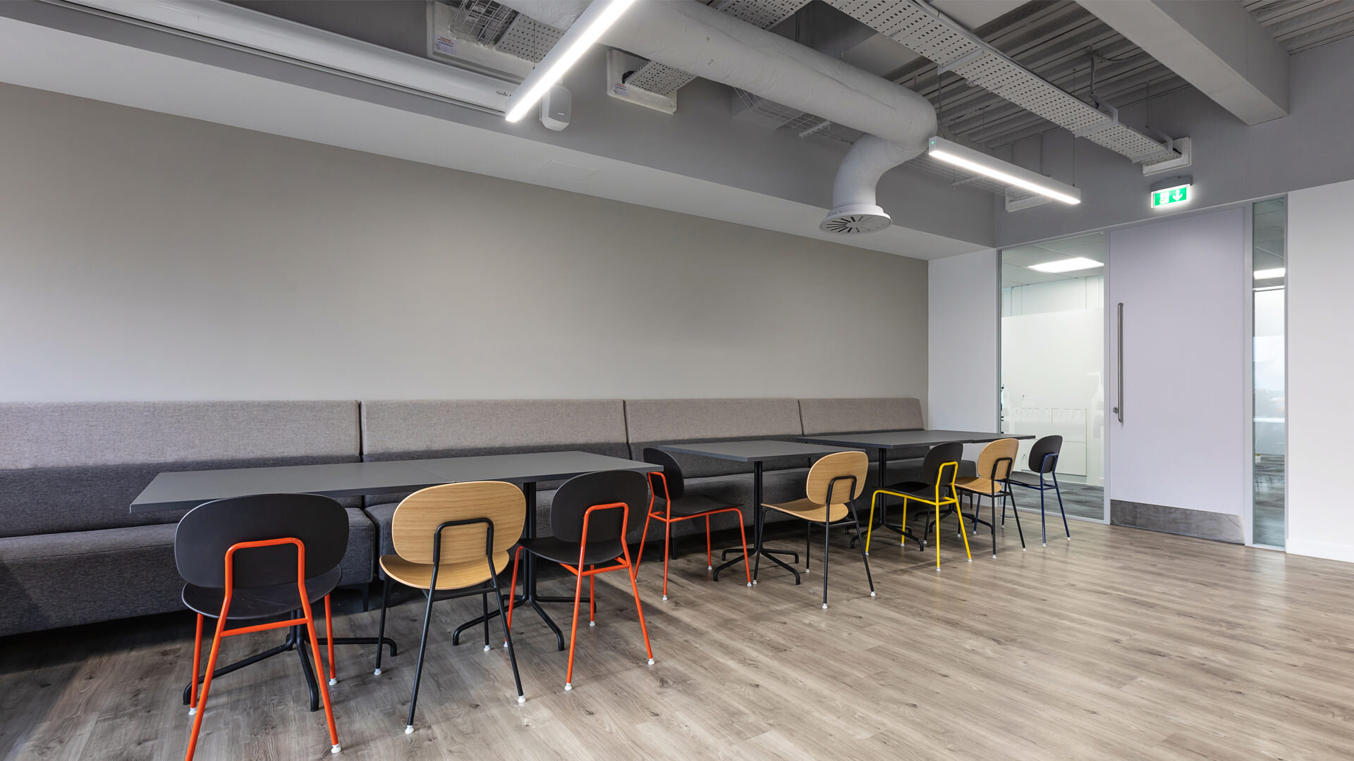 office workplace canteen kitchen pantry island tiles design interior exposed ceiling linear booth seating grey white red yello