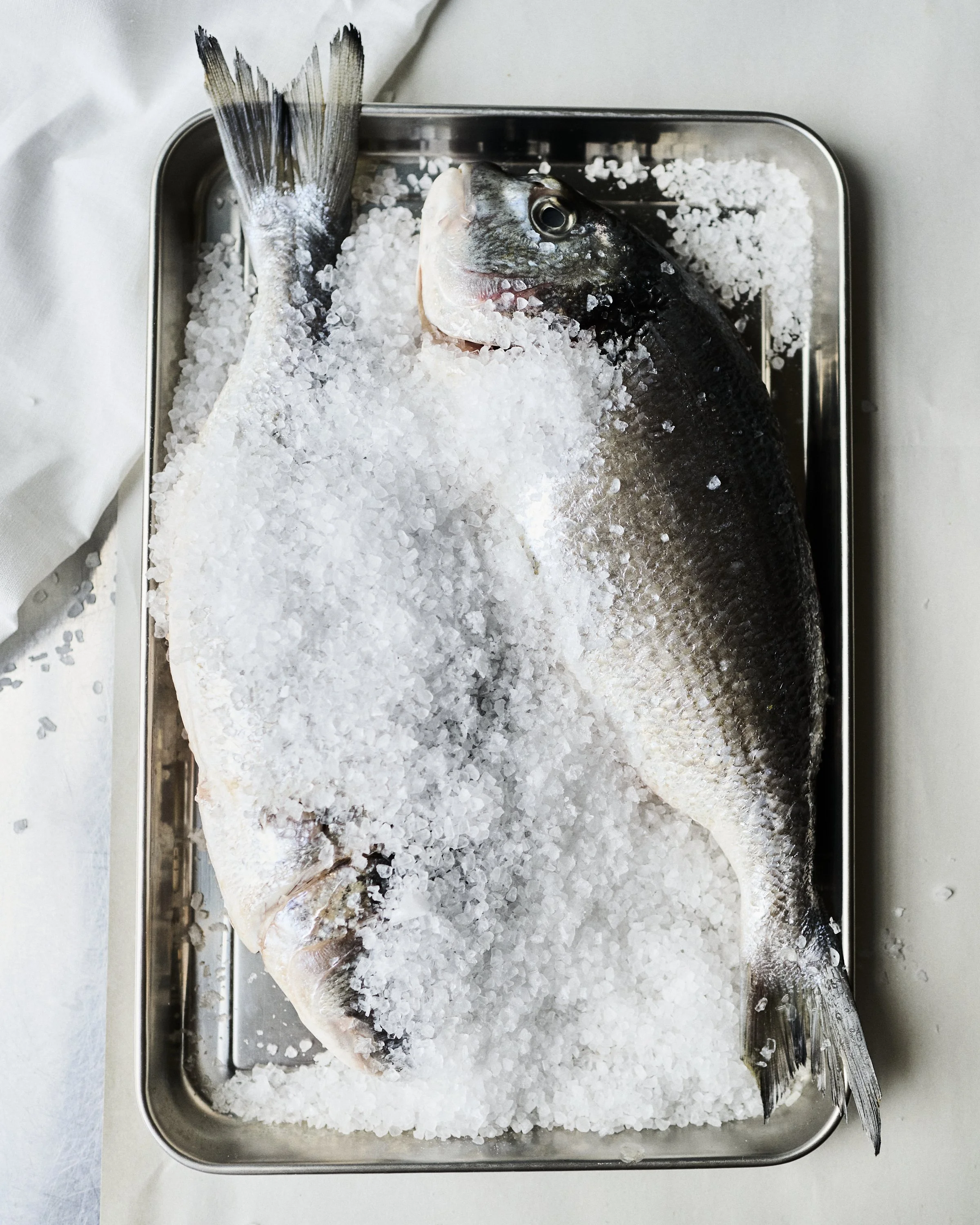 Whole fish on a metal tray covered with crushed ice.