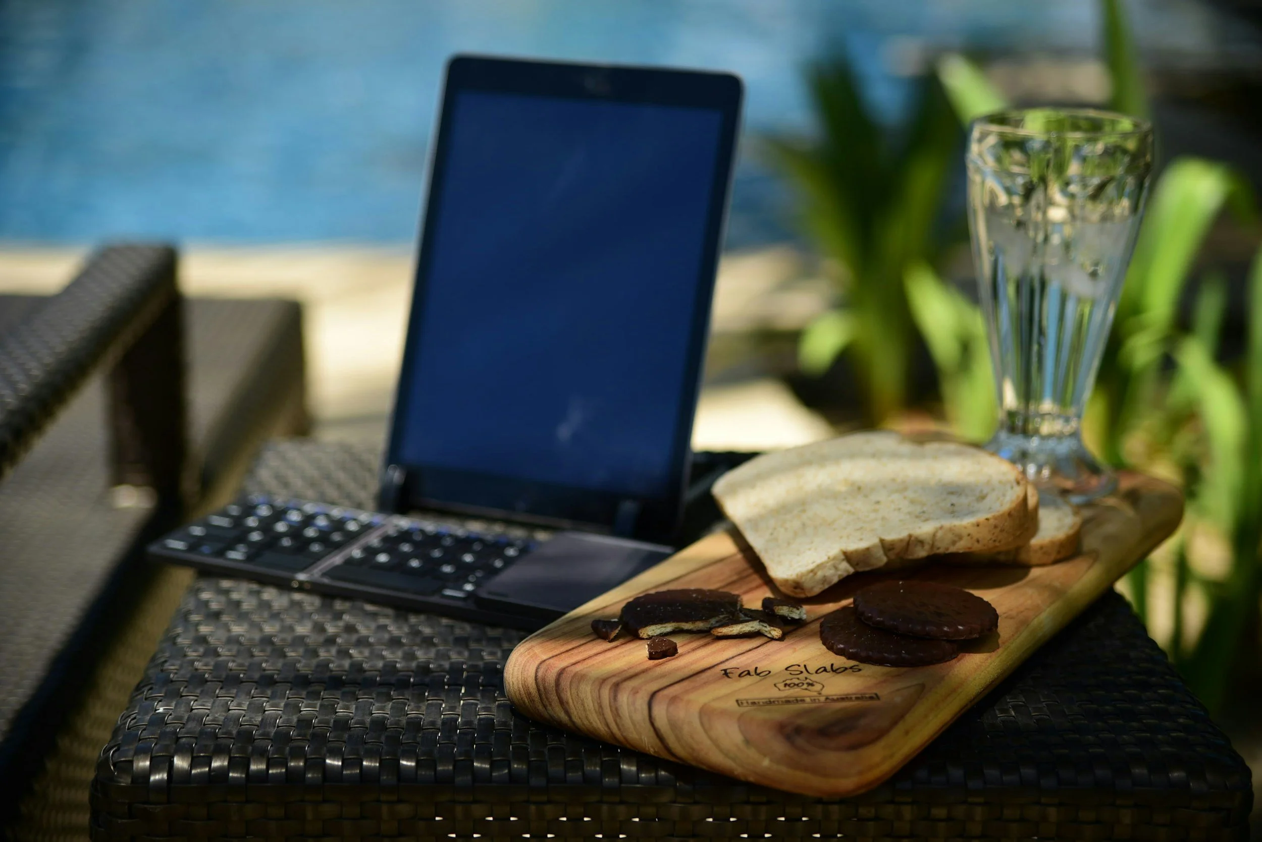 tablet, keyboard, snacks, lounge chair by the pool for a relaxing summertime workspace