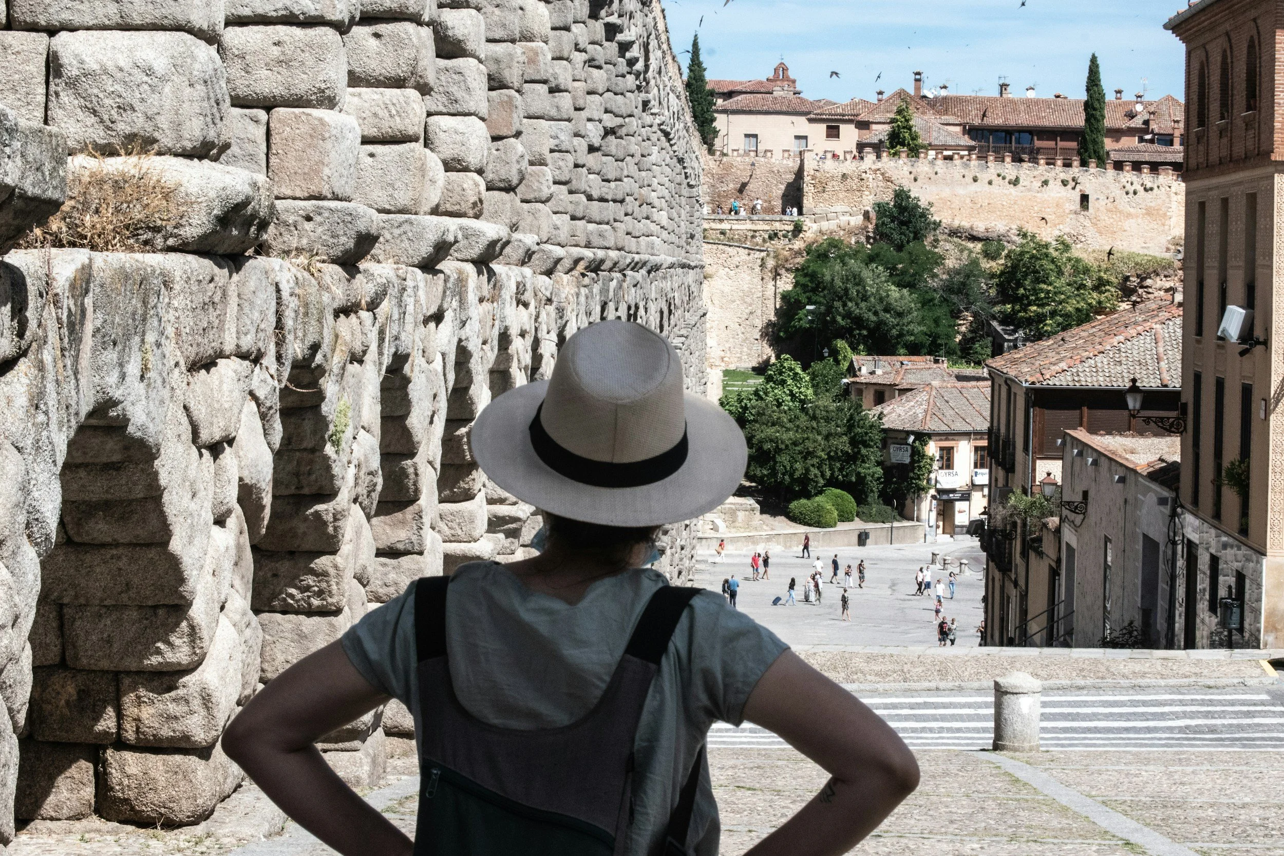 Tourist taking in the sites of village square with ancient stone walls and buildings