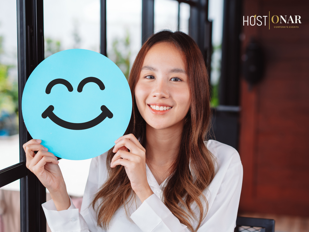 Smiling woman holds a blue smiley-face circle; HOST | ONAR logo in corner. Image conveys client appreciation and human-centered relationship building.