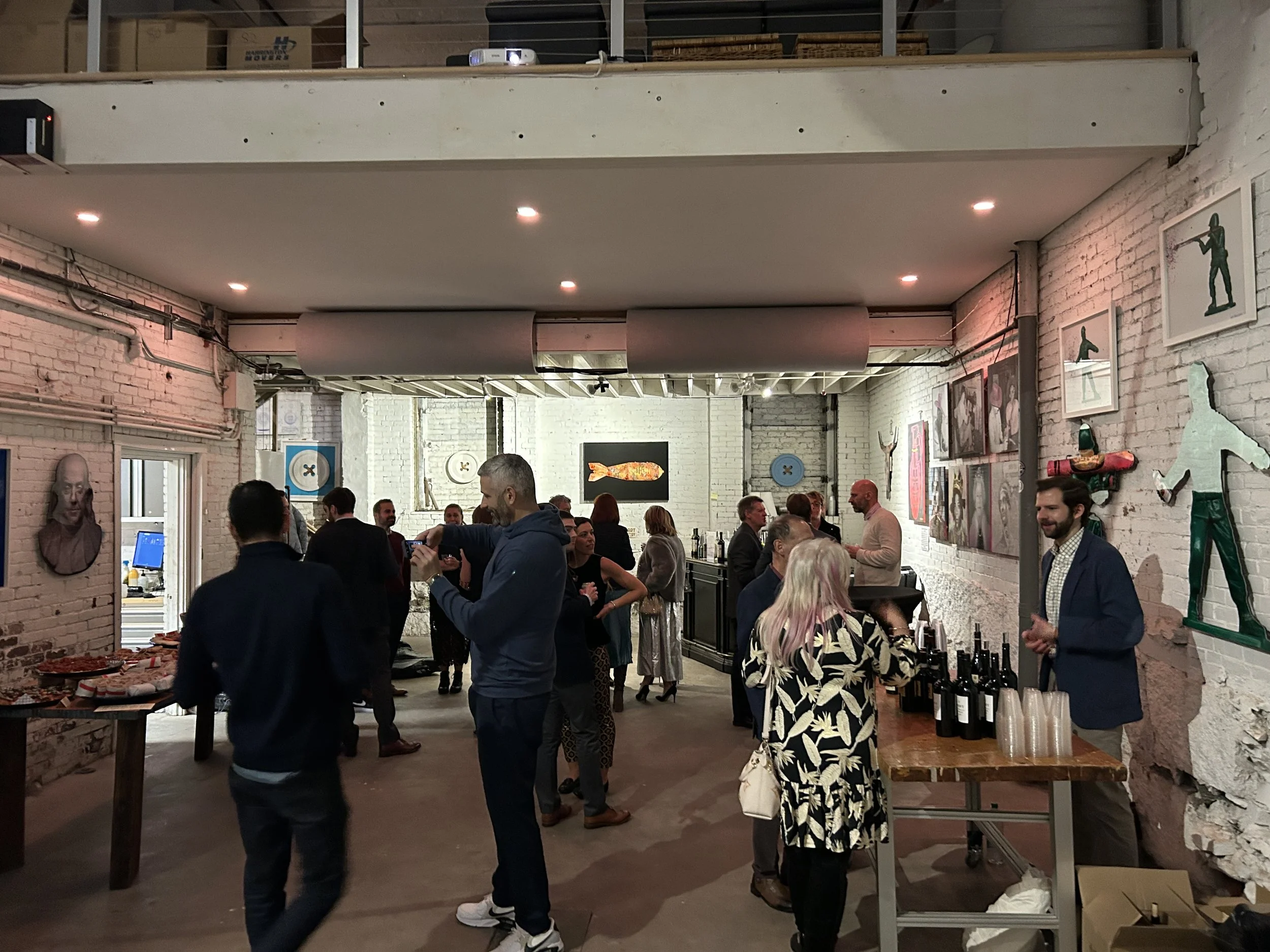 Guests gather inside a warmly lit experiential event space featuring food stations, drinks, artwork, and social interaction during a HOST Events activation in Boston.