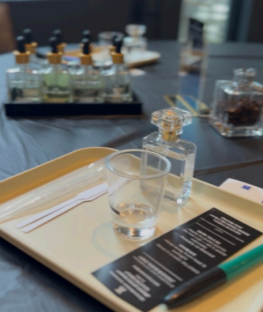 Perfume blending workshop station with fragrance bottle, mixing glass, scent strips, and blending guide