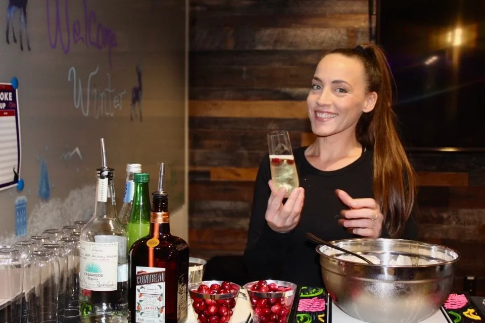 HOST bartender behind bar holding drink and smiling at holiday office party