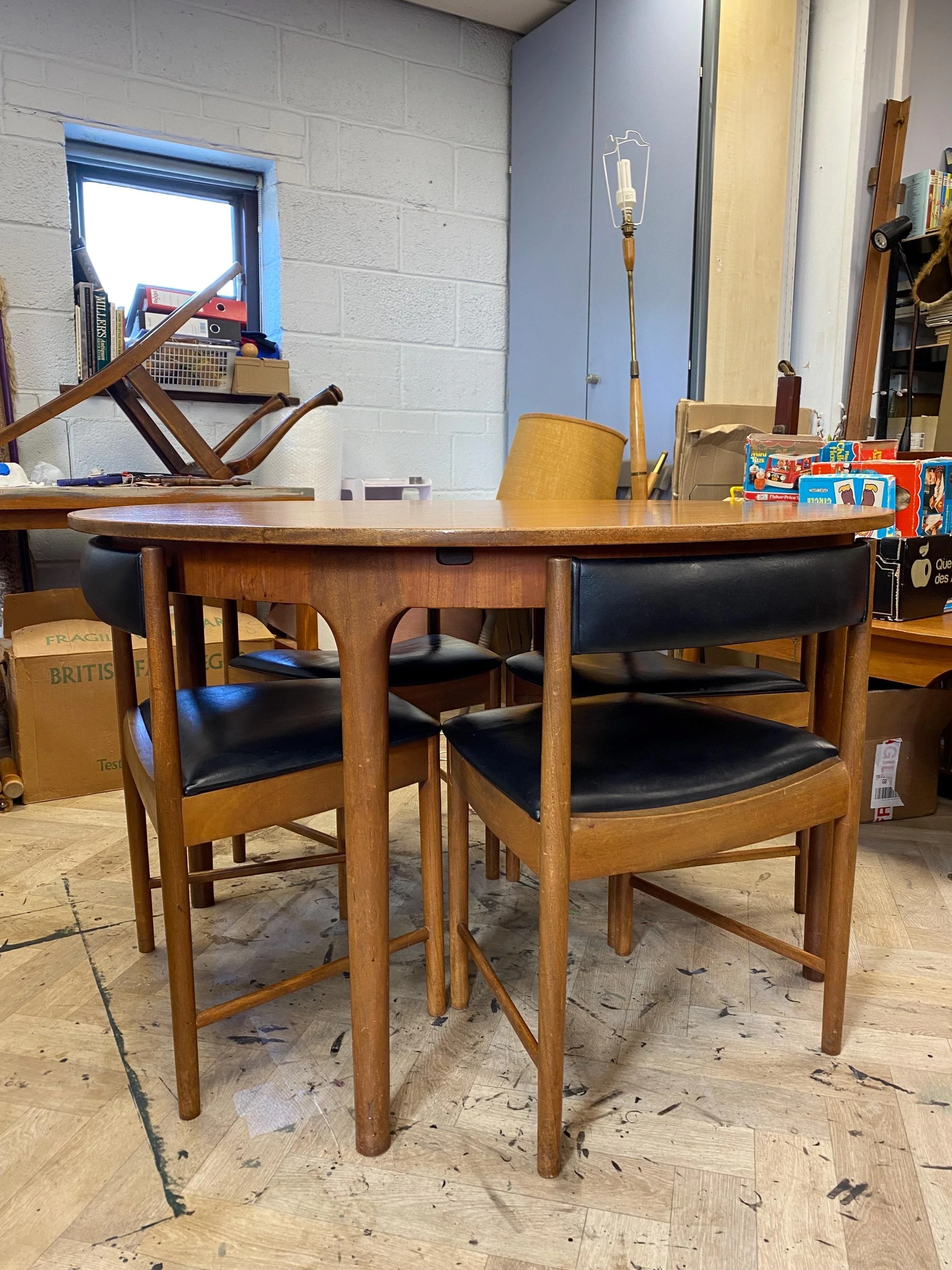 1960s McIntosh circular teak extending dining table and four black vinyl chairs