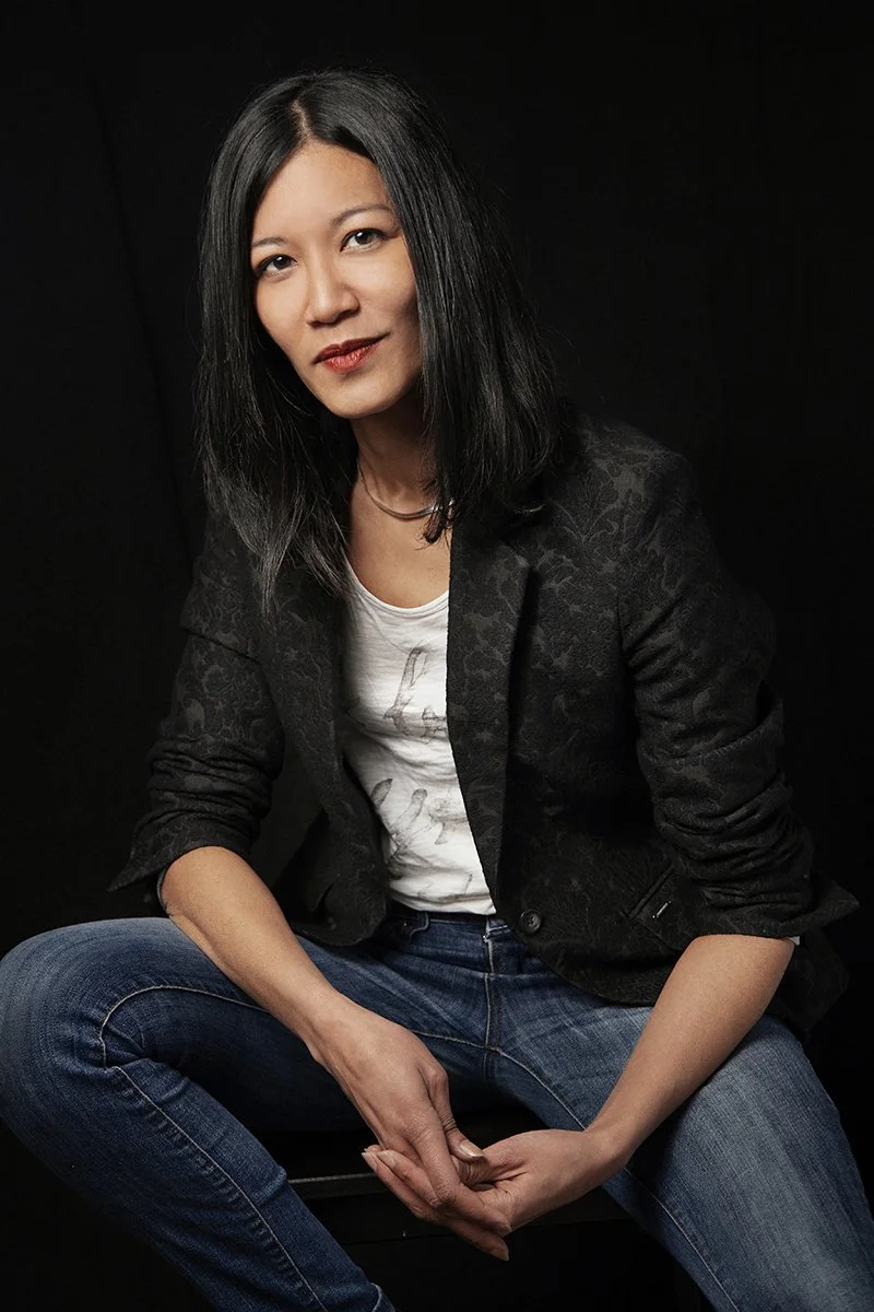 Woman in black jacket and white t-shirt sitting on a stool