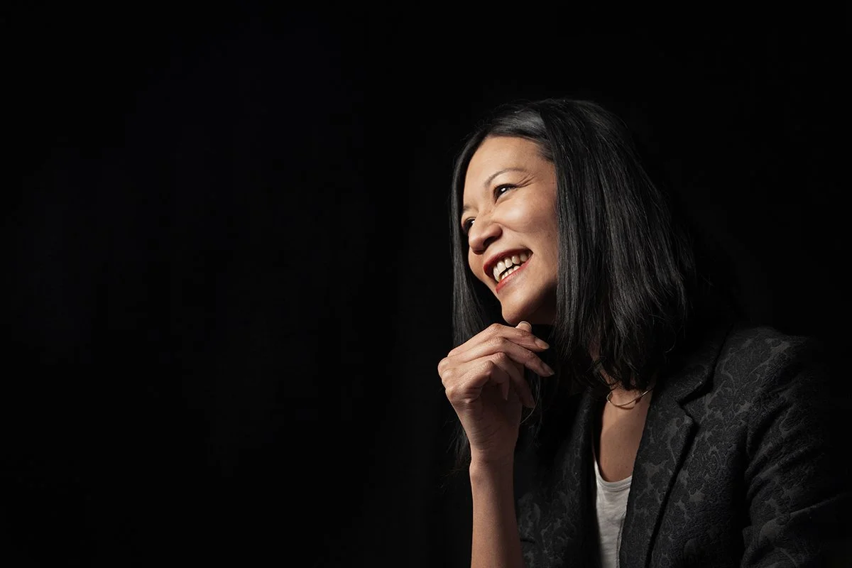 Profile of young woman in black jacket on black background