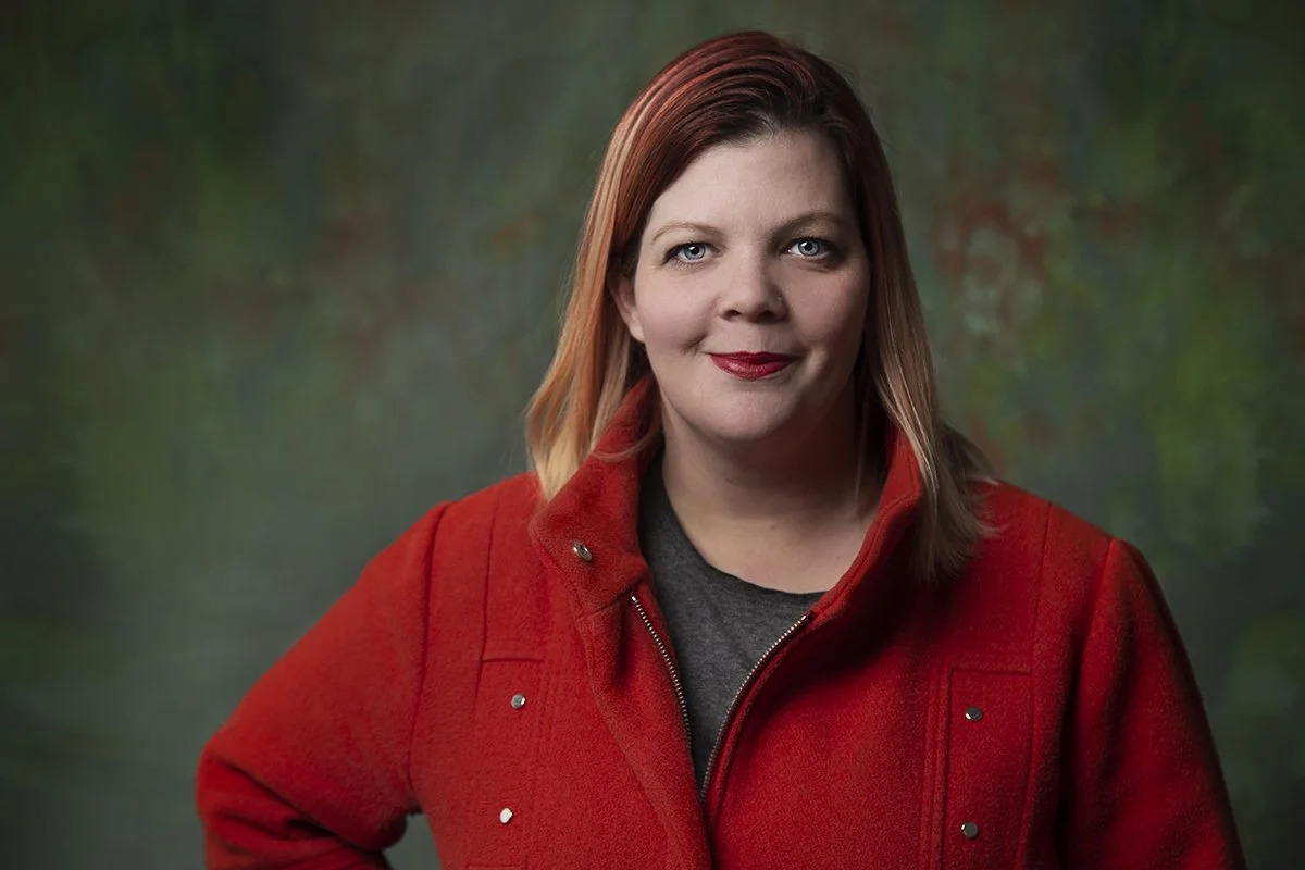 Smiling red-haired woman in red coat against green background with flowers