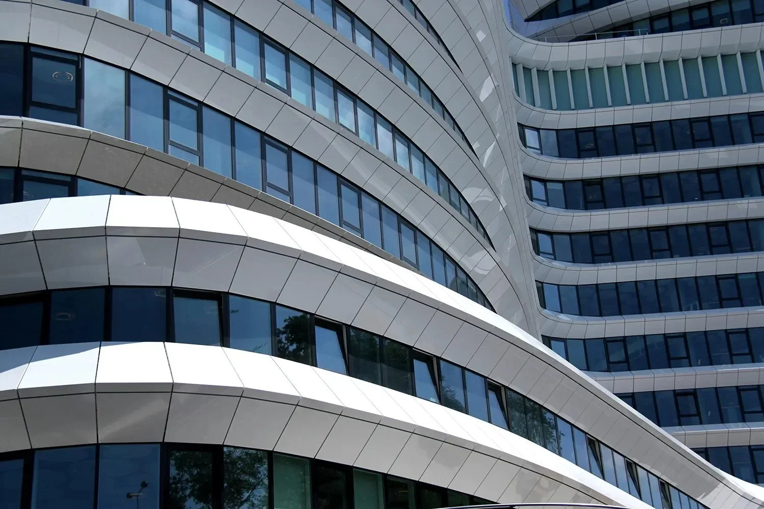 Close-up view of a modern high-rise building with curved balconies and blue-tinted windows.