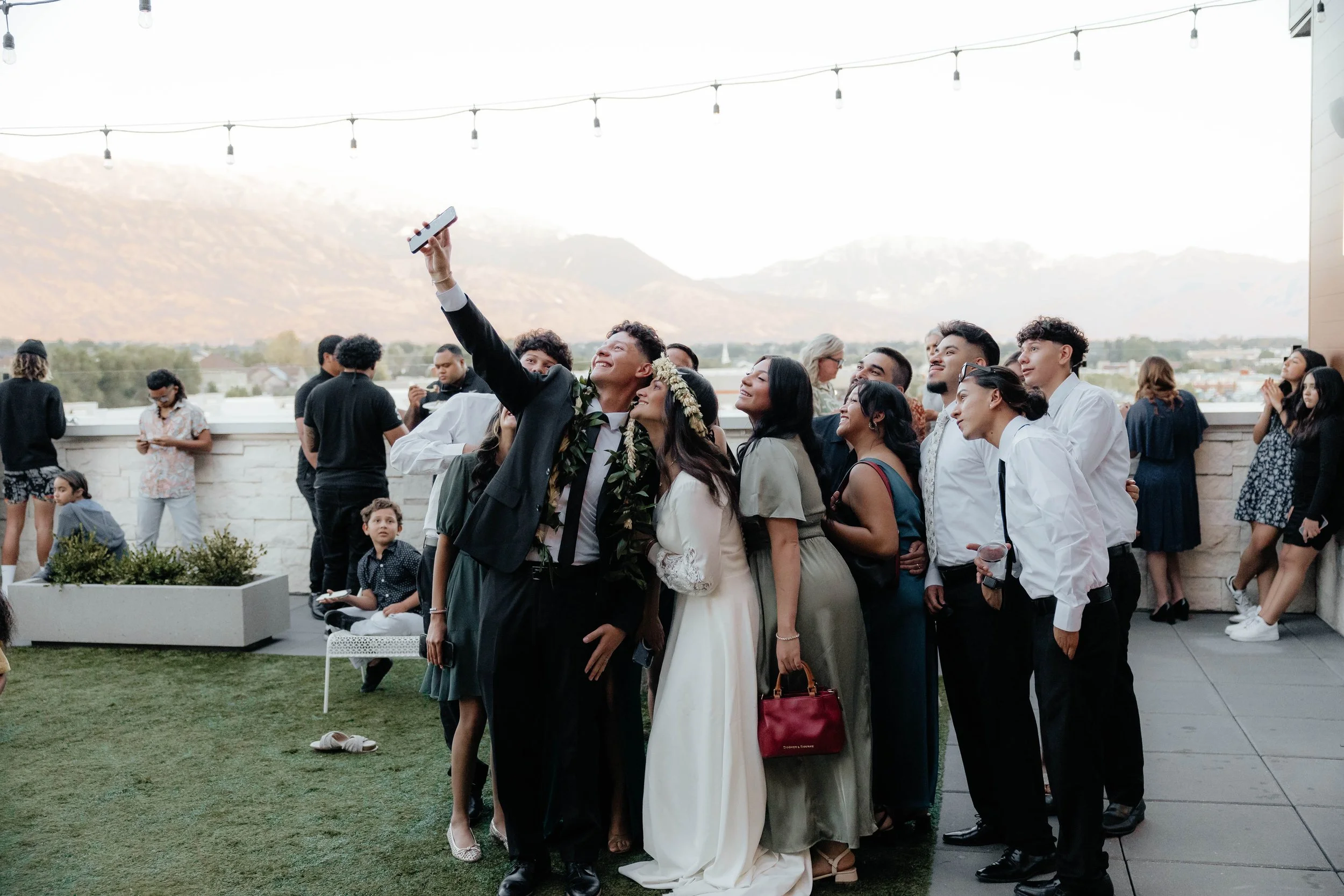 Bride and groom take a selfie with wedding guests in the courtyard.