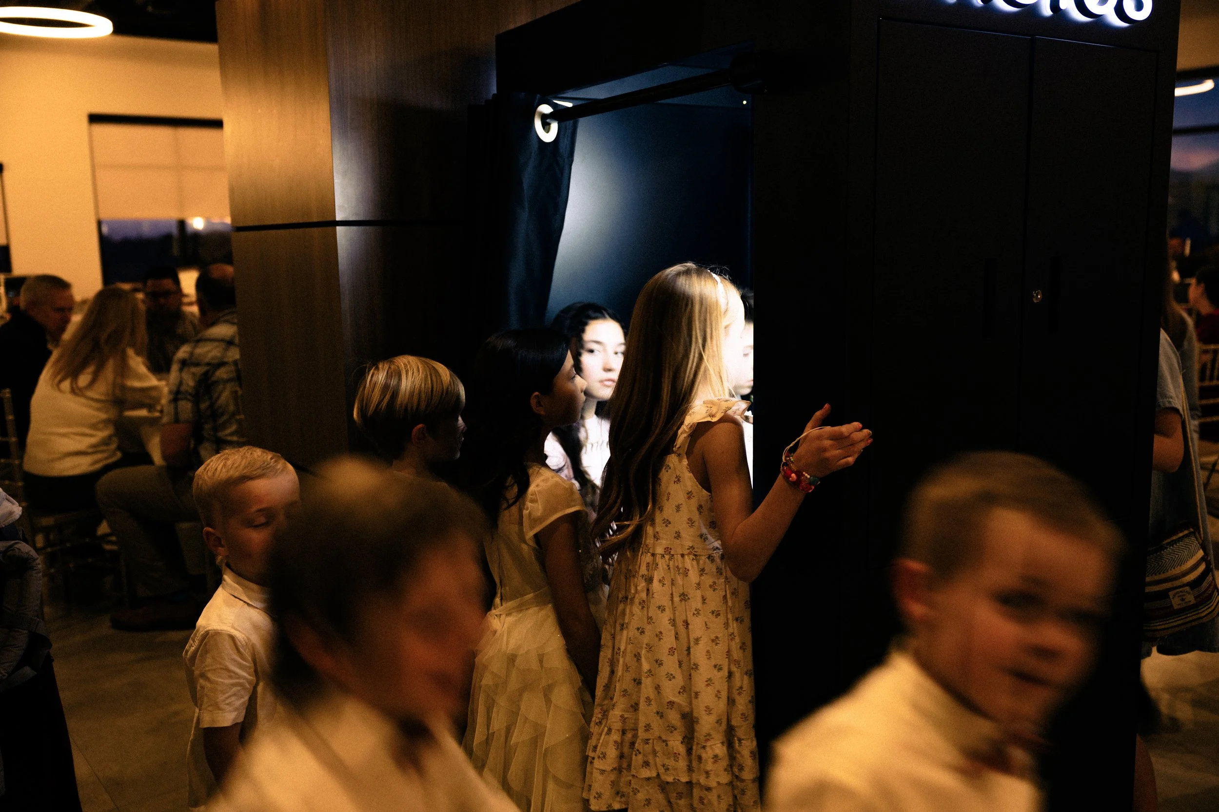 Wedding guests look into the photobooth and someone is taking a picture.