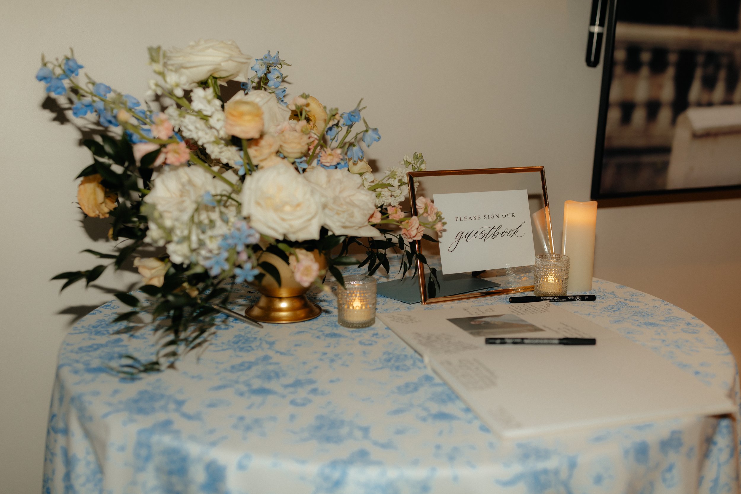 Wedding welcome table with a bouquet of flowers and a guestbook with pens.
