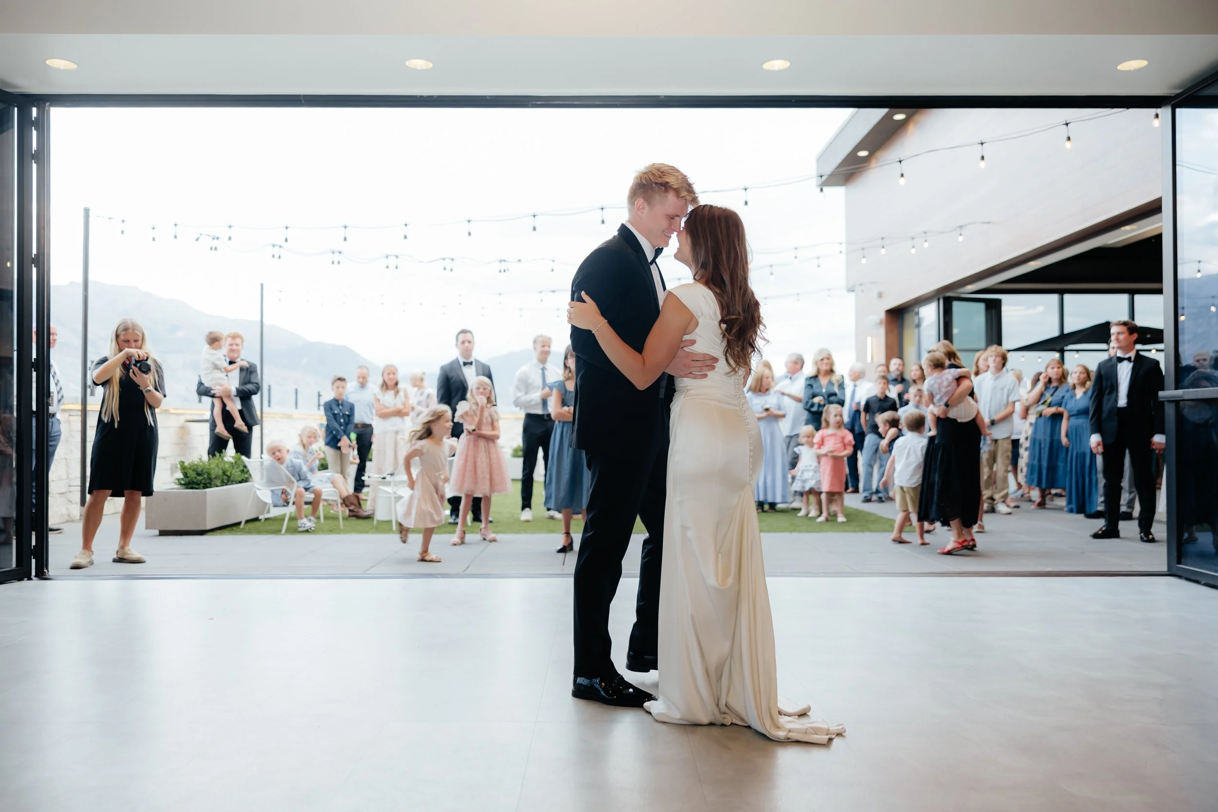 Newlywed couple shares their first dance with guests watching in the courtyard.