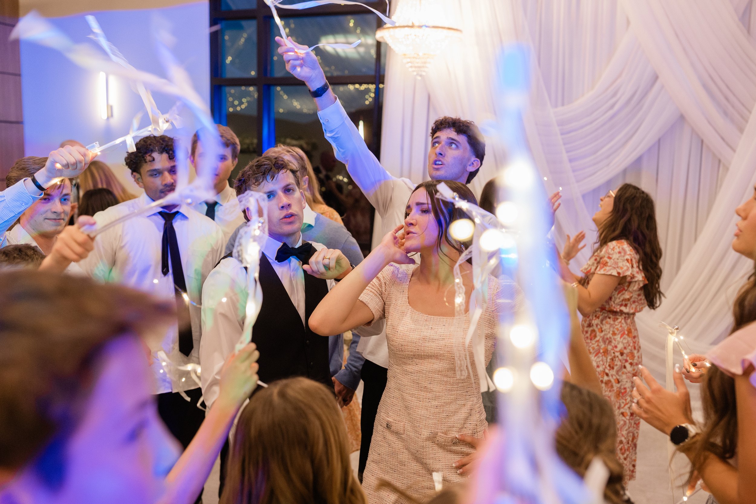 Bride and groom dance with guests on the dance floor.