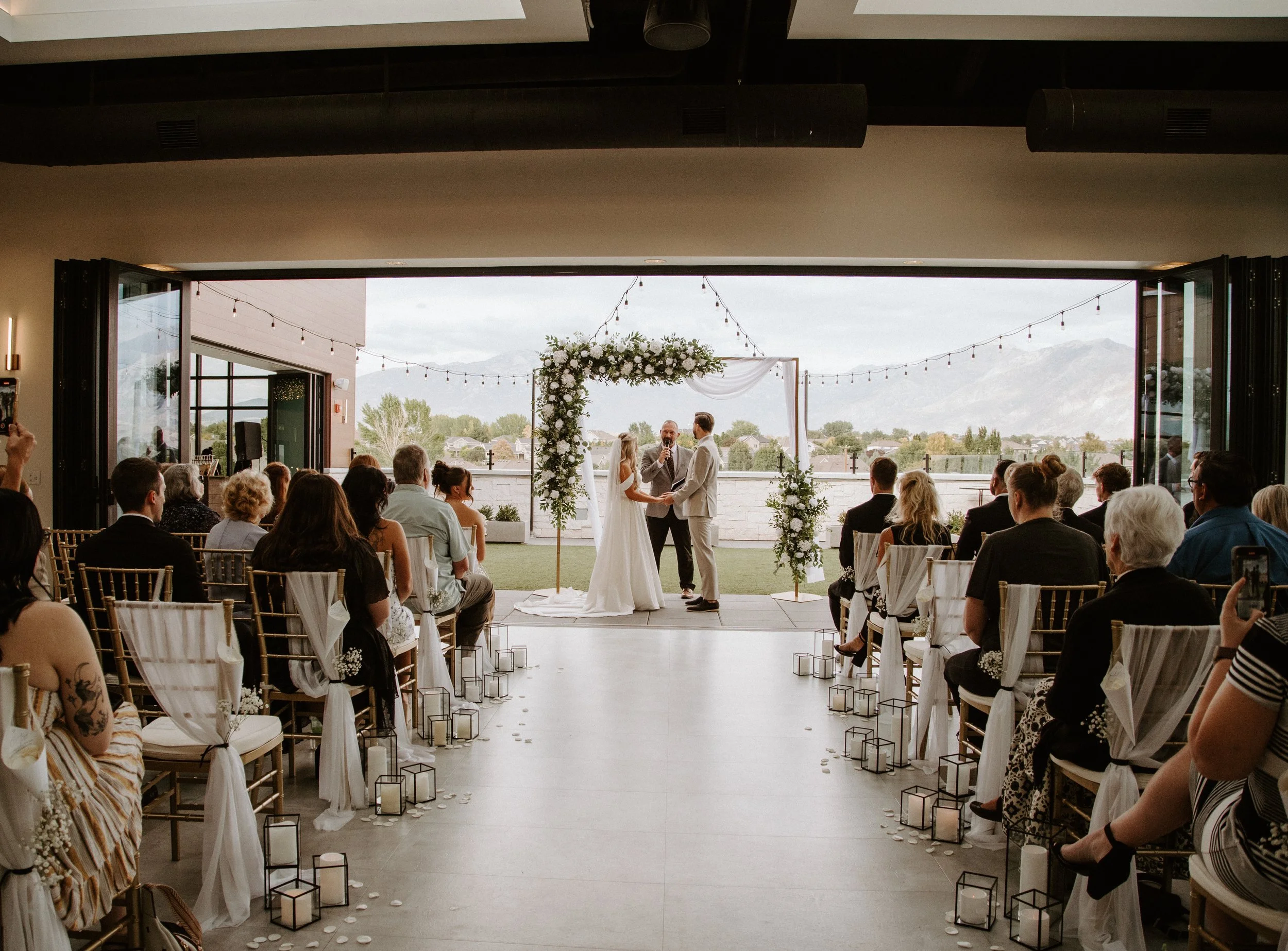 A wedding aisle decorated with white candles leading to a courtyard wedding ceremony.