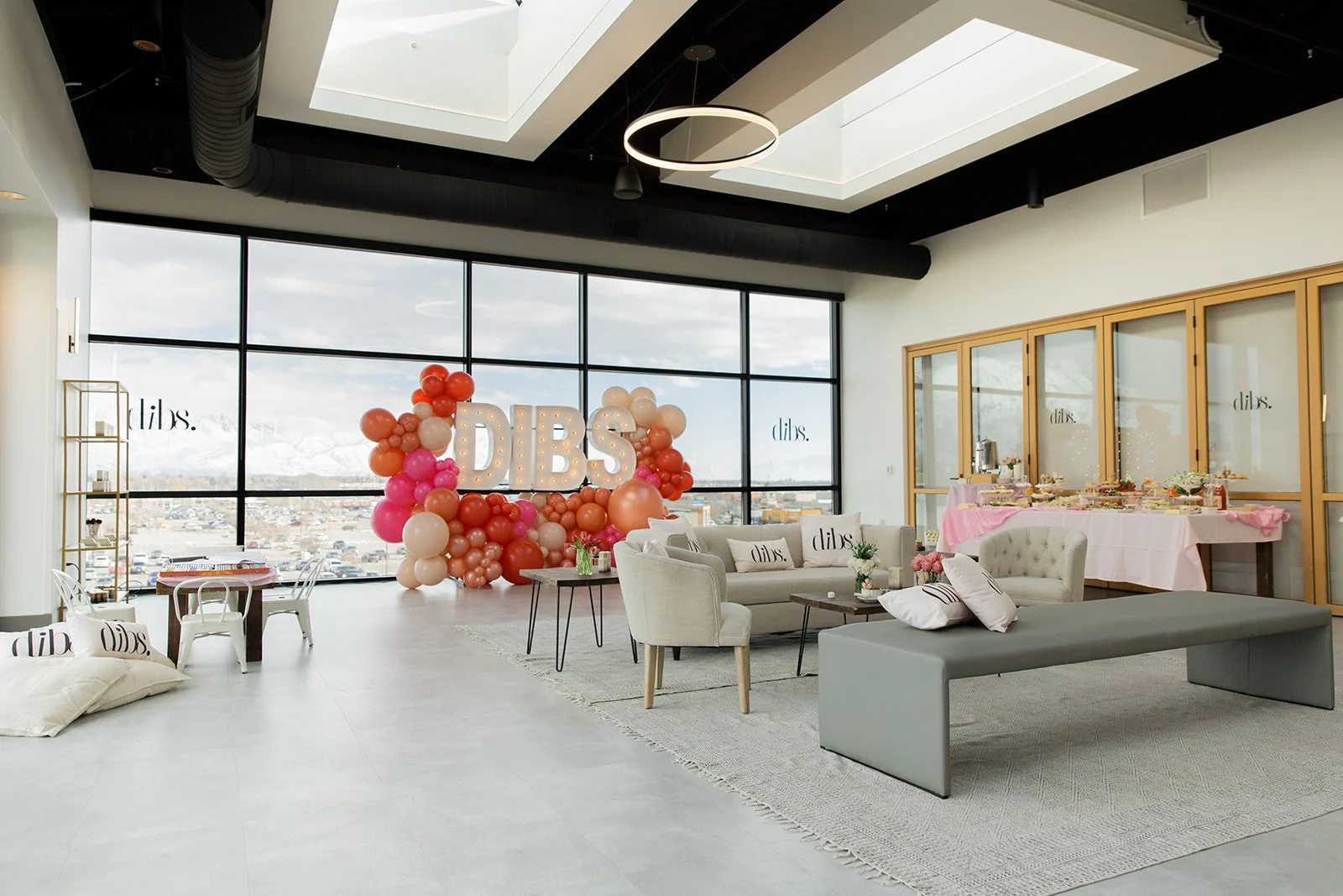 Corporate event setup with marquee letters, balloons, a couch, and bench.