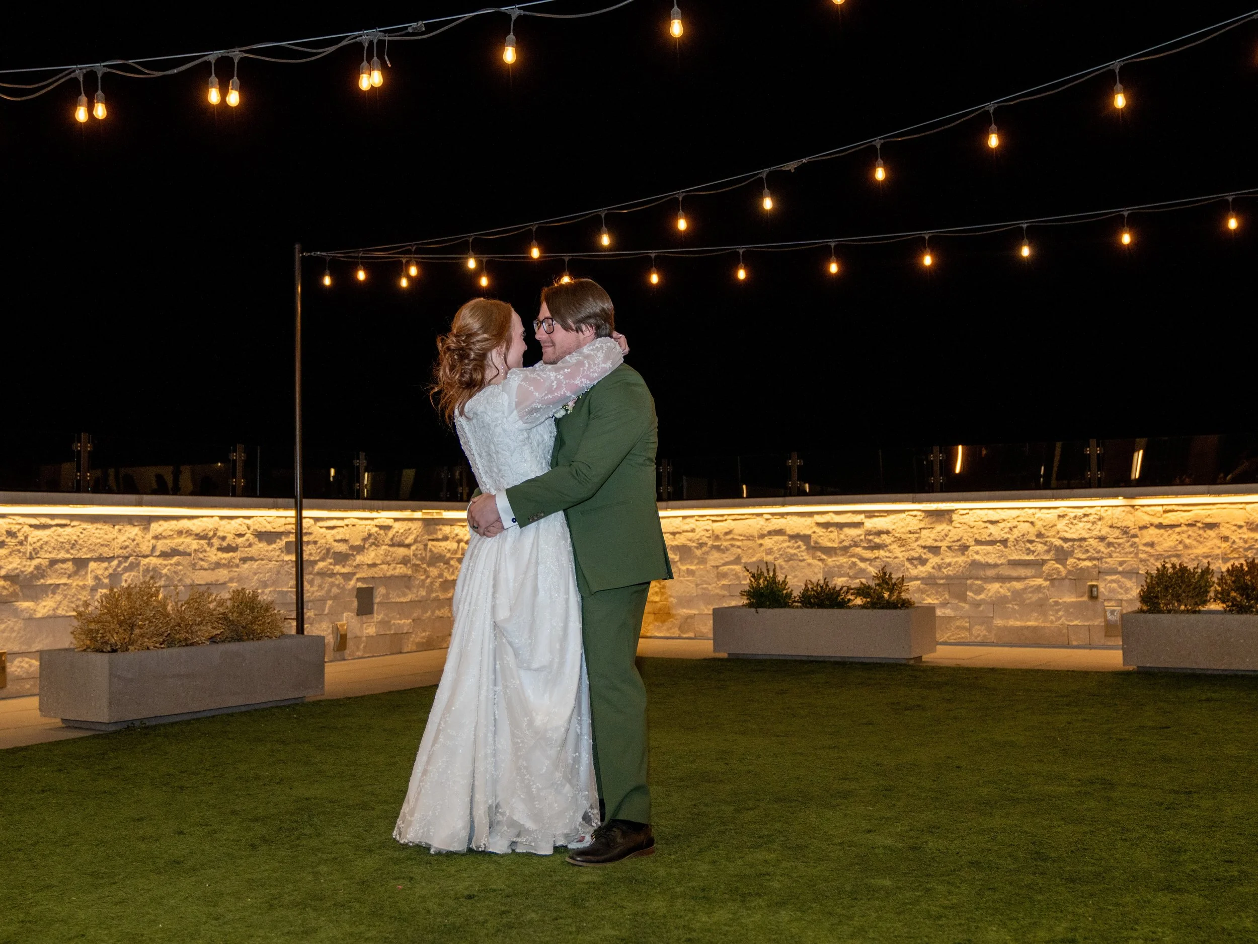 Bride and groom dance in the courtyard under bistro lights.