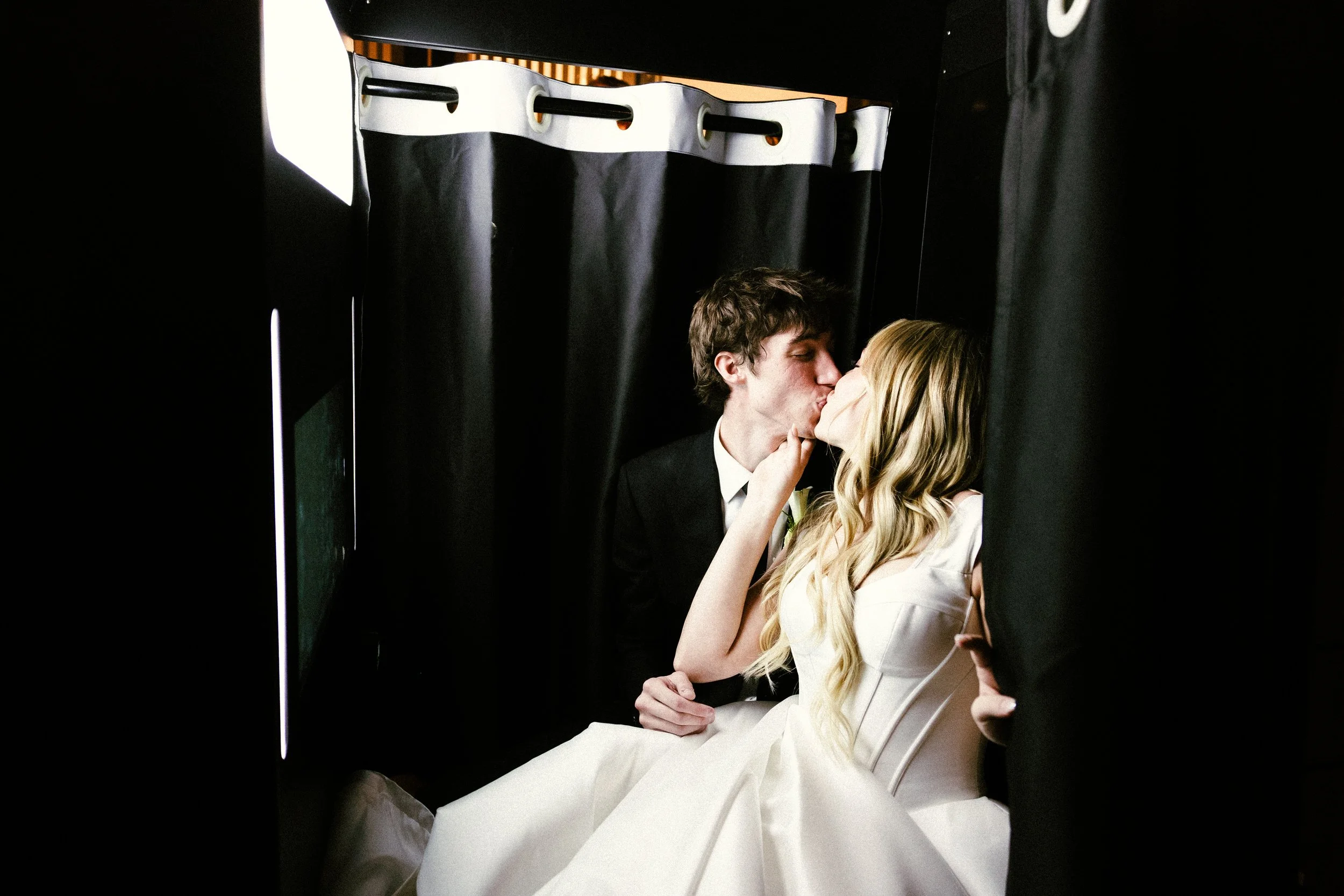 Bride and groom kiss in a photo booth.