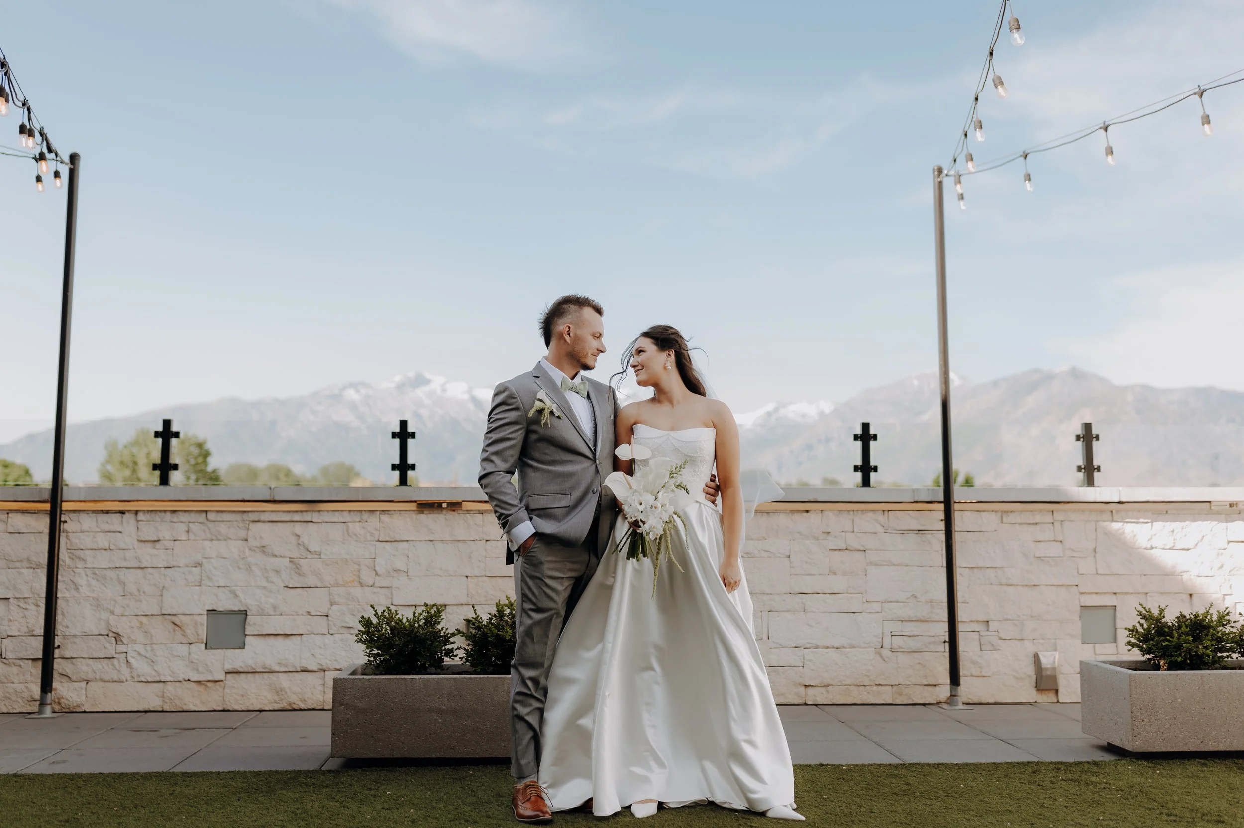 Bride and groom stand side by side looking into each other's eyes.