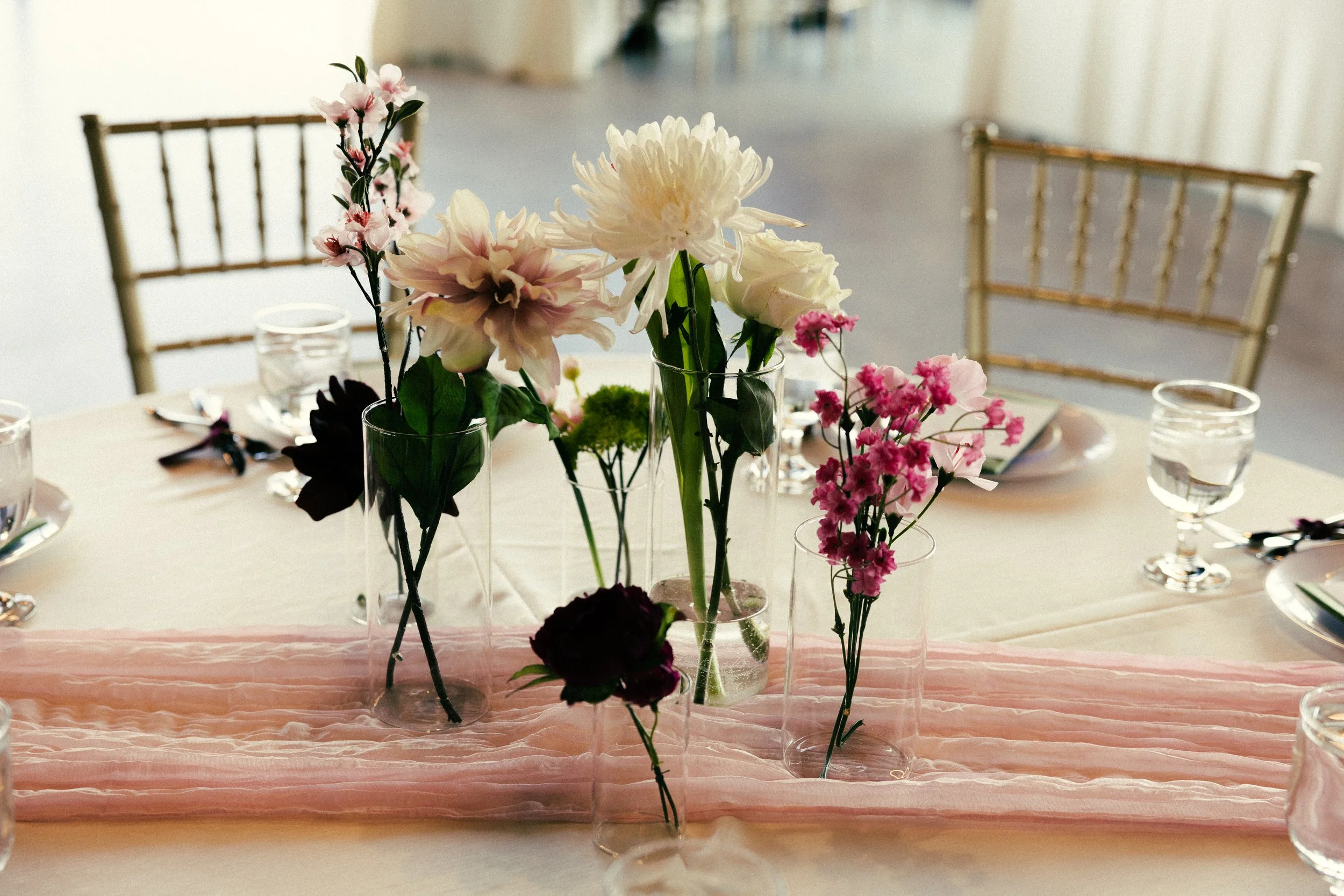 Round table centerpiece with white flowers, pink flowers, and a light pink table runner.
