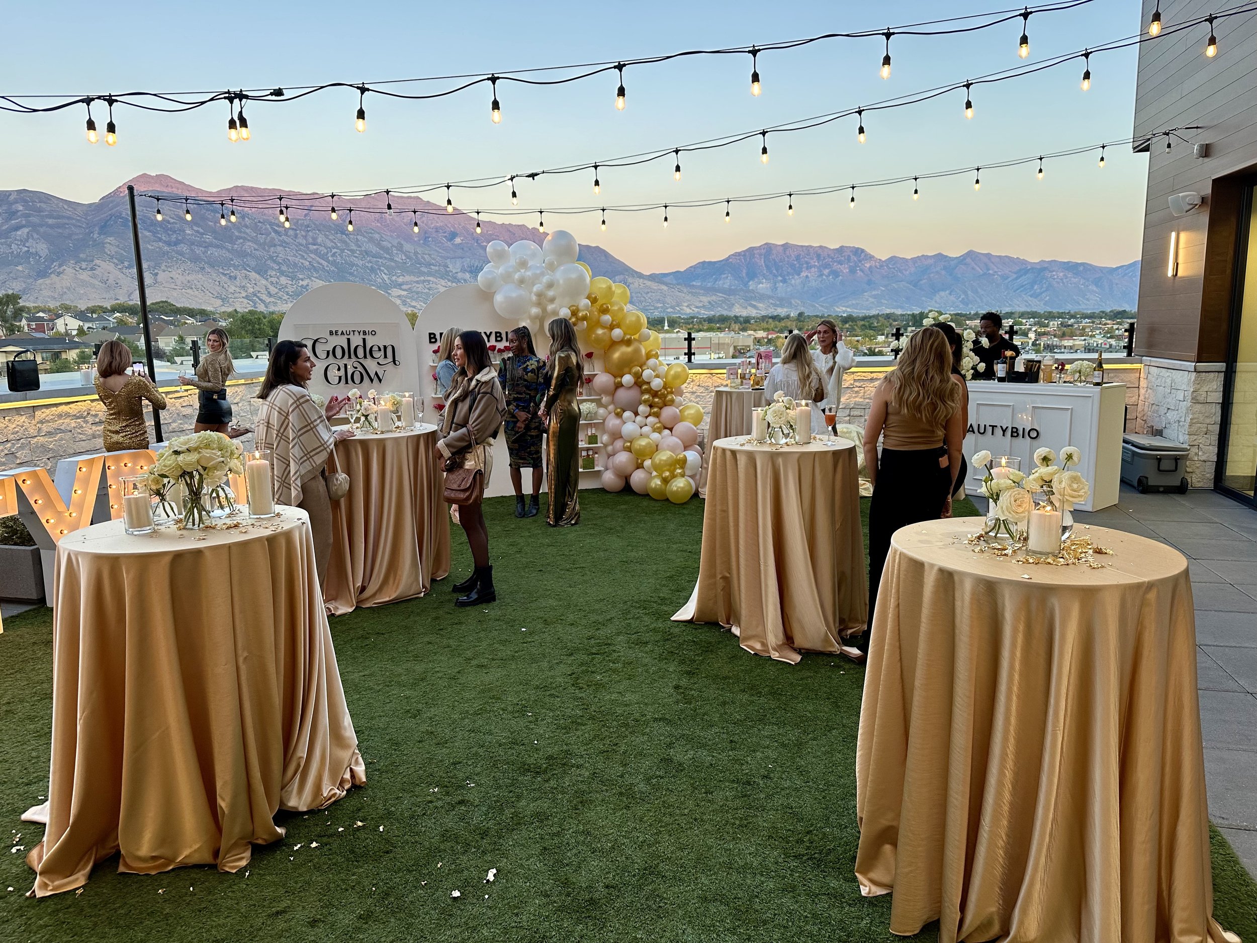 Women mingle outside in the courtyard near bistro tables covered with gold linens.